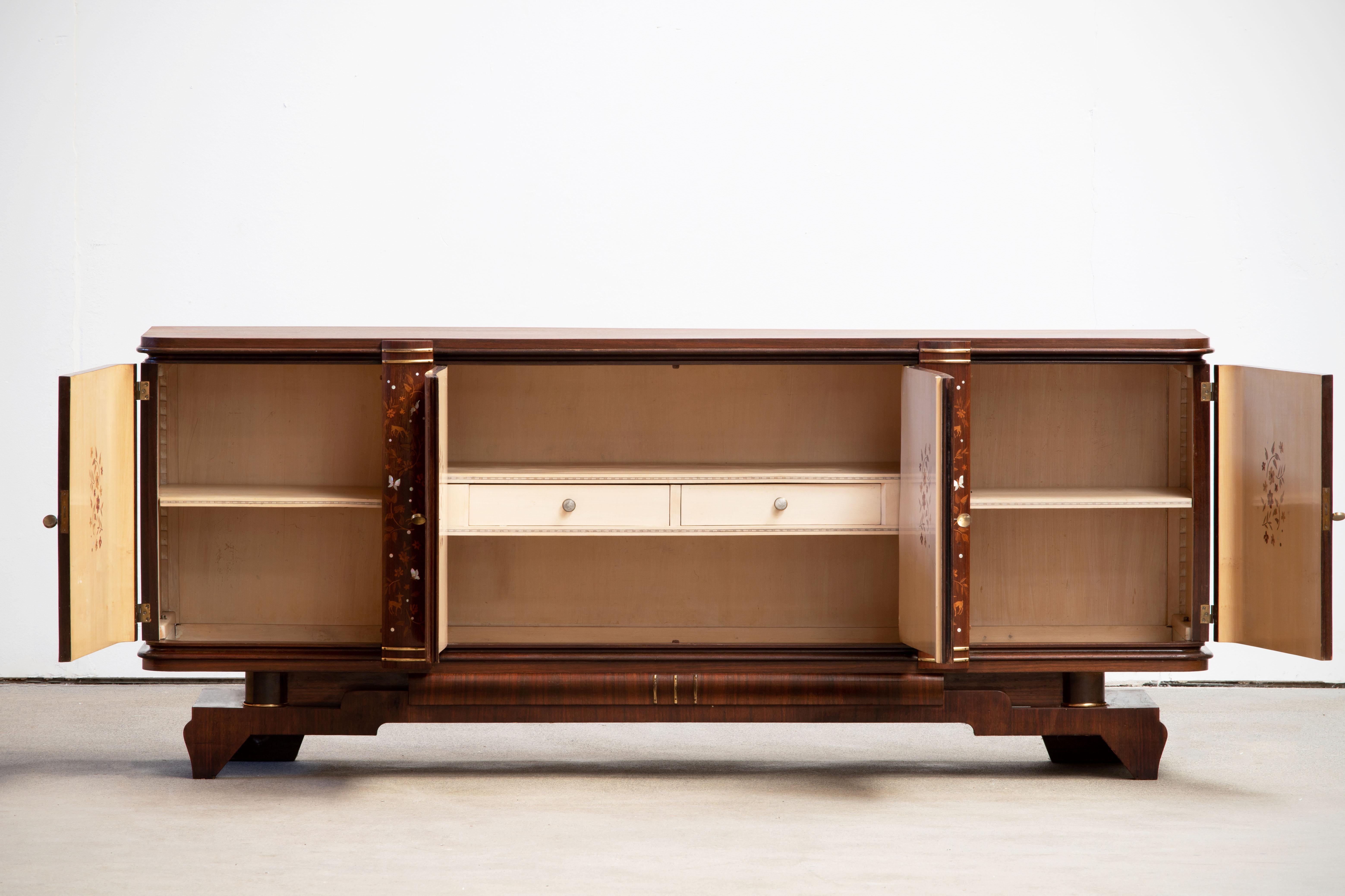 French Art Deco sideboard, credenza. The sideboard features stunning Macassar ebony wood grain with a thin decorative mother of pearl inlay design with butterflies and birds. The inside is also a piece of art with wooden pieces and mother of pearl