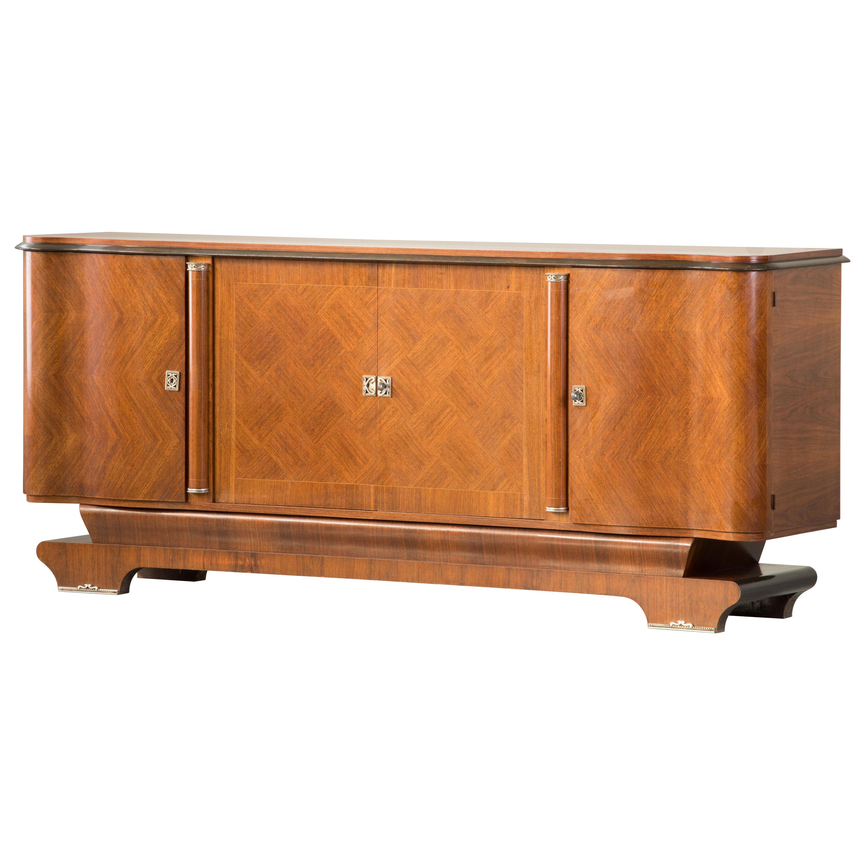 A handsome marquetry mahogany sideboard in the style of Jules Leleu, early 20th century.
This sideboard features three compartments with shelves with a drawer in the central one. The interior is made of Sycamore. This is a very nice piece, in good