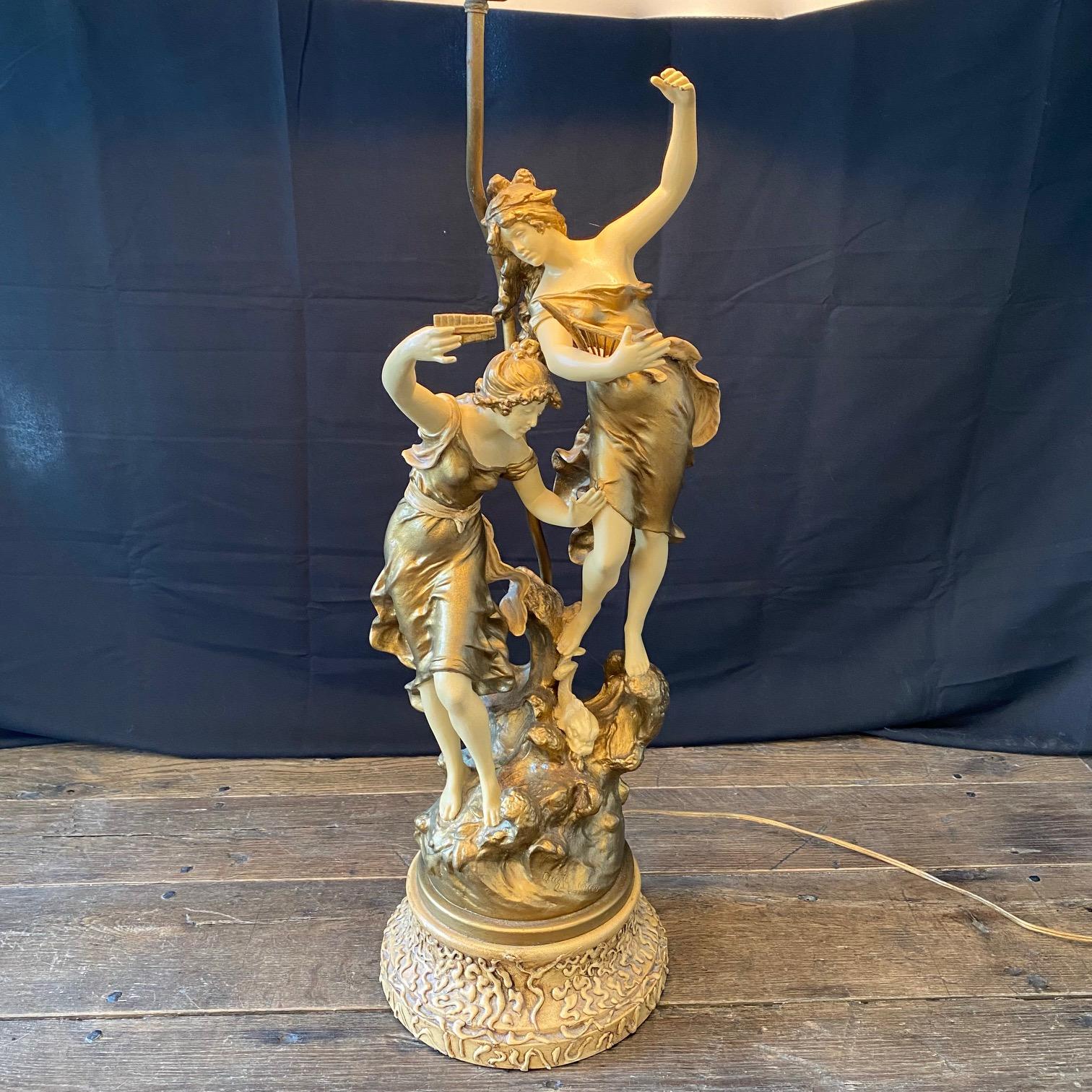 Elegant and beautiful French tall table lamp with two seductive female musical women figures on the waves of the base. Each woman holds a musical instrument such as a harp, in her hand. Signed Auguste Moreau on the base. Wired to American standards,
