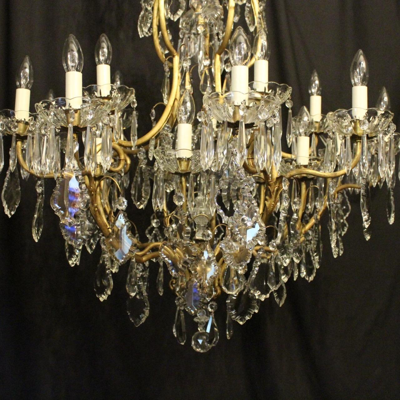 A large French gilded cast brass and crystal 21 light birdcage form triple tiered antique chandelier, the 20 tiered reeded leaf scrolling arms with glass bobeche drip pans and bulbous candle sconces, issuing from an foliated cage form interior with