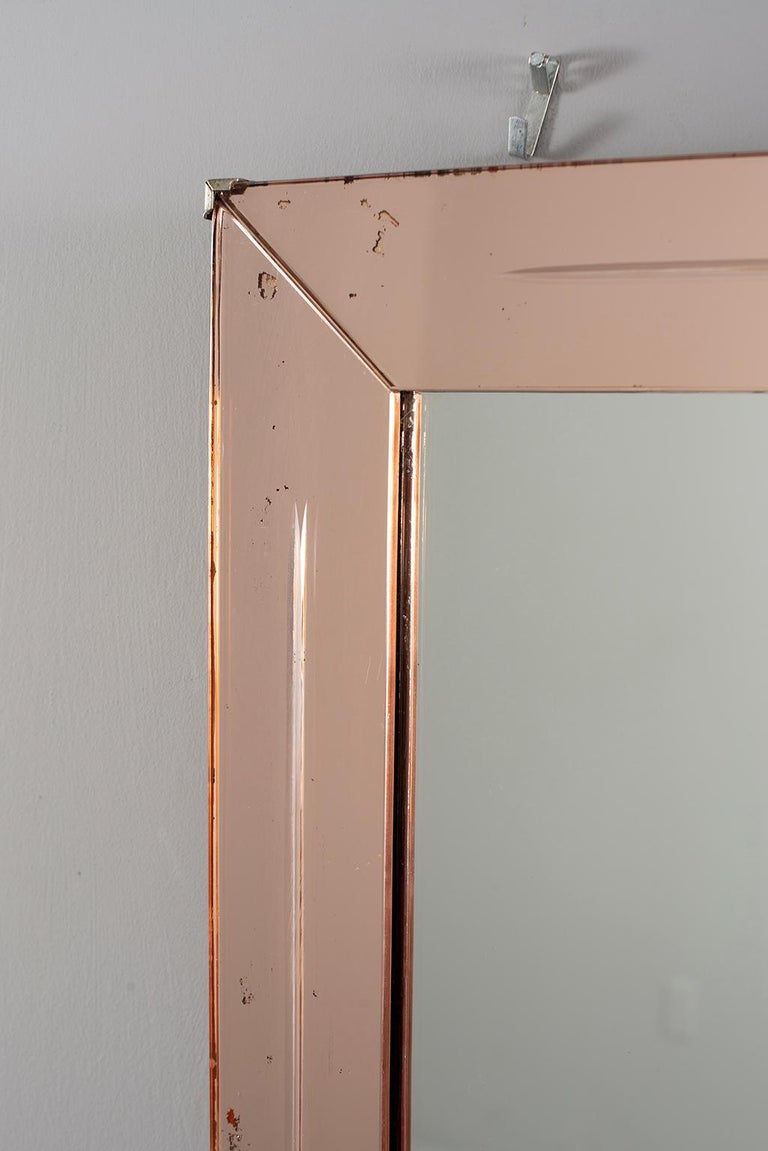 French Venetian style mirror with pale peach colored mirrored frame, circa 1920s. Some scattered loss of silvering to mirror and frame. Unknown maker.  Actual Mirror Size:  38” h x 21” w

   