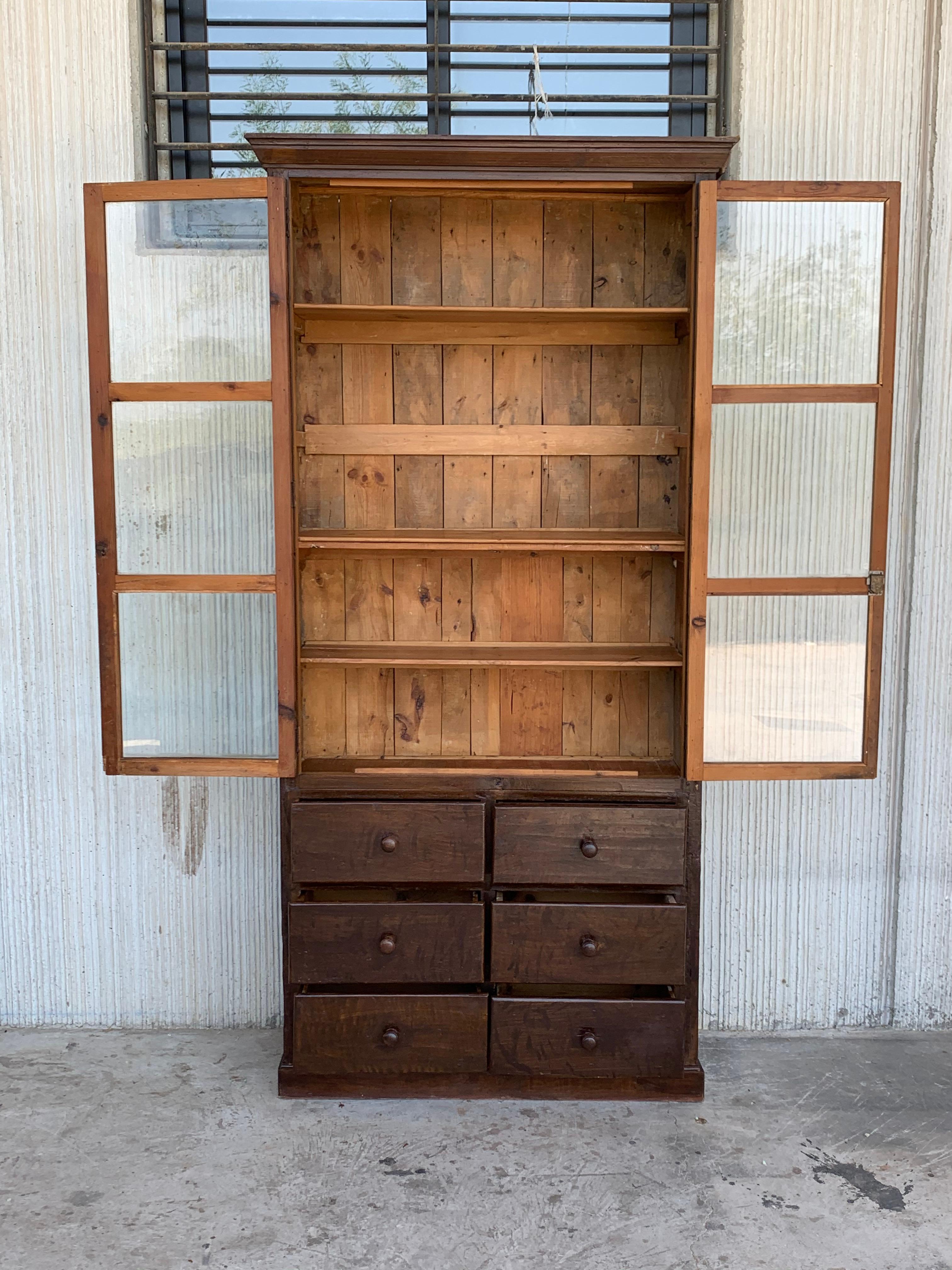 19th century Spanish cupboard or bookcase with glass vitrine, constructed from a solid walnut and original glasses of this perior. Features a coffered case fronted by two large doors with glasses. It has a six drawers in the low part. This massive