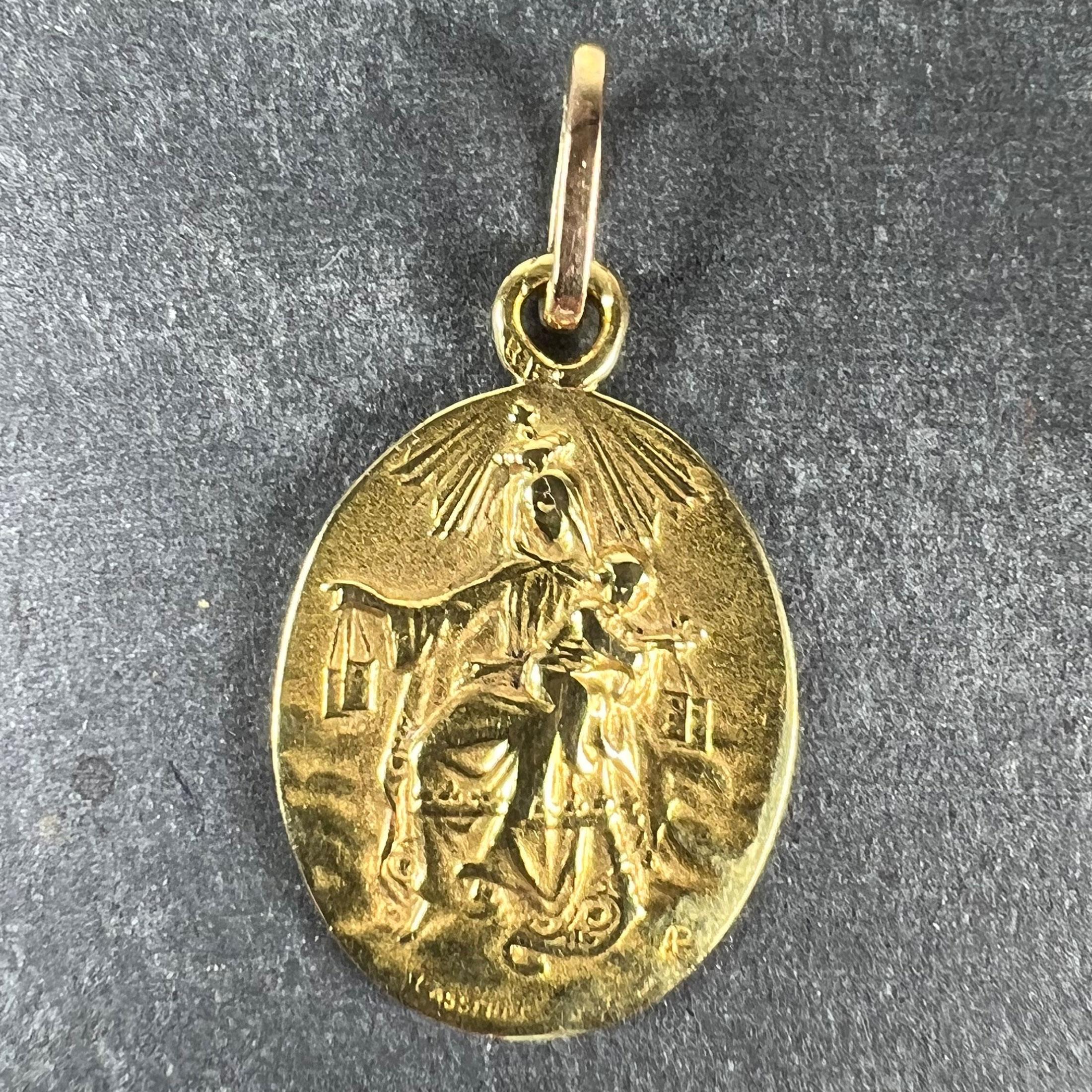 A French 18 karat (18K) yellow gold charm pendant designed as an oval medal with a relief of The Blessed Virgin Mary as a Madonna with the infant Christ holding a set of devotional scapulars, representing 'St Scapulaire'. To the reverse a relief of