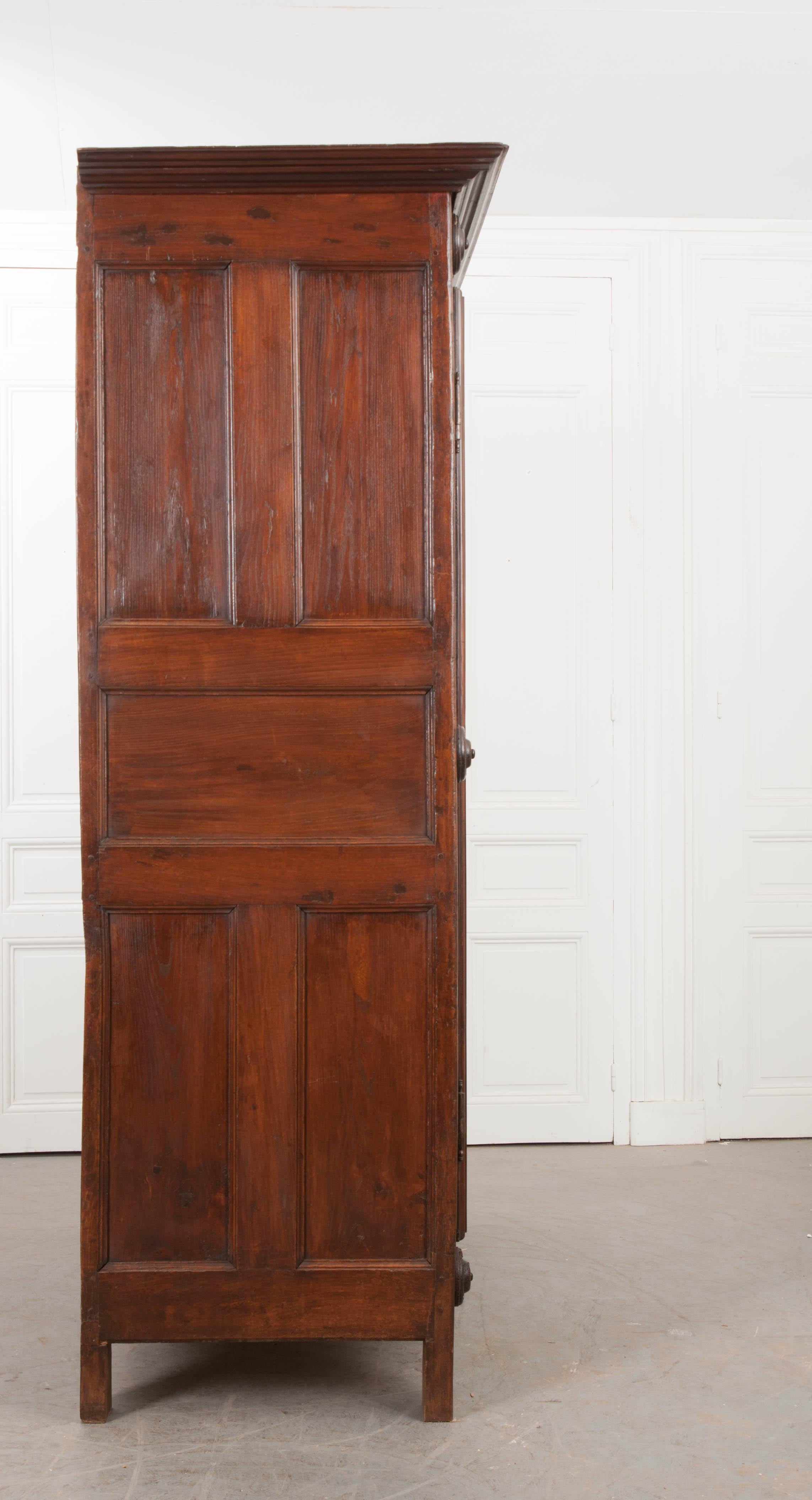 This large oak two-door armoire is from France, circa 1780s, and has a rich, warm patina. Characteristic of the Louis XIII style (1610-1643), it features boldly carved and paneled doors with steel hinges, surrounded by seven turned roundels, shaped