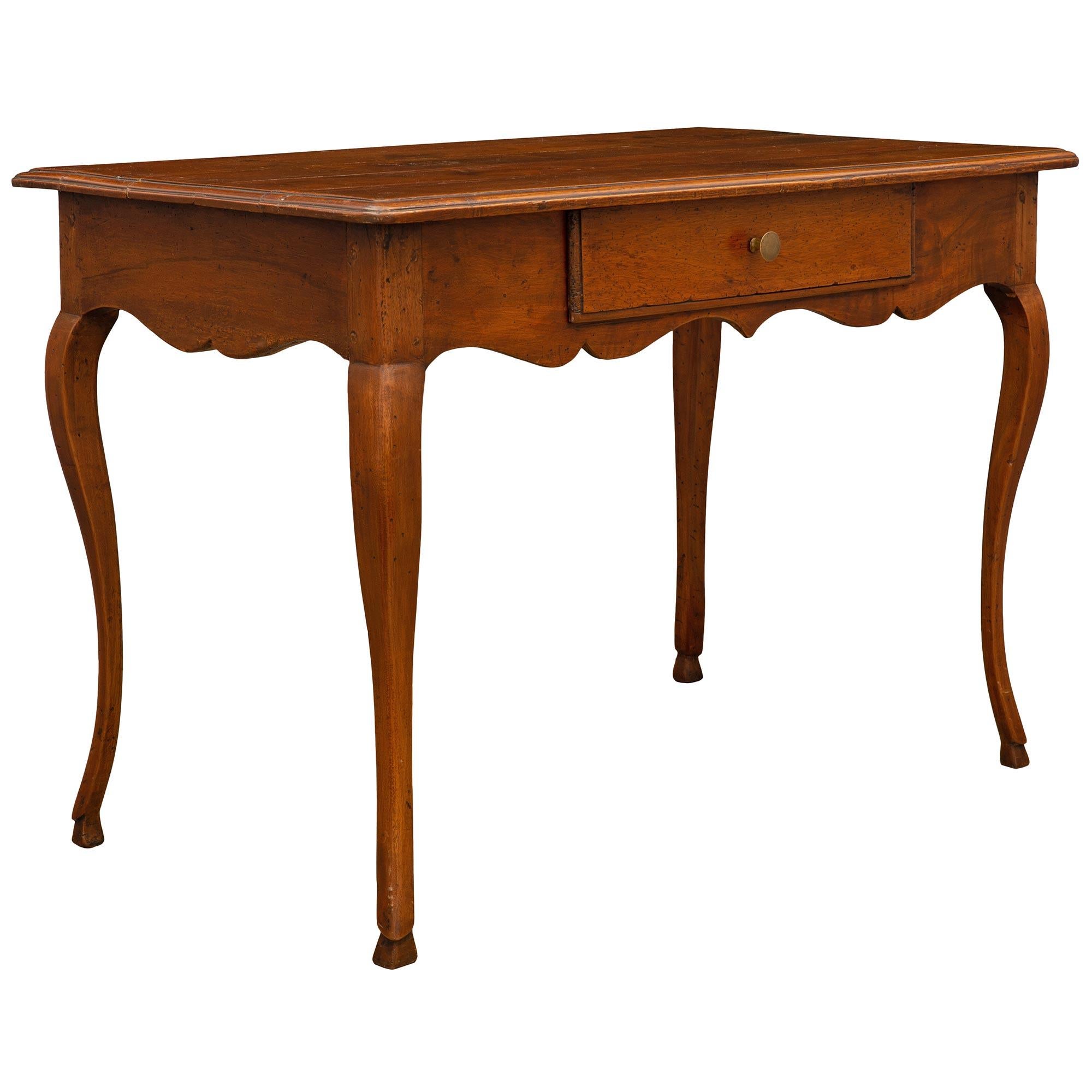 A charming and very elegant French late 18th century Louis XV period oak desk/side table. The table is raised by lovely slender cabriole legs with fine hoof feet. The apron displays a most decorative scalloped shape repeated at each side while the
