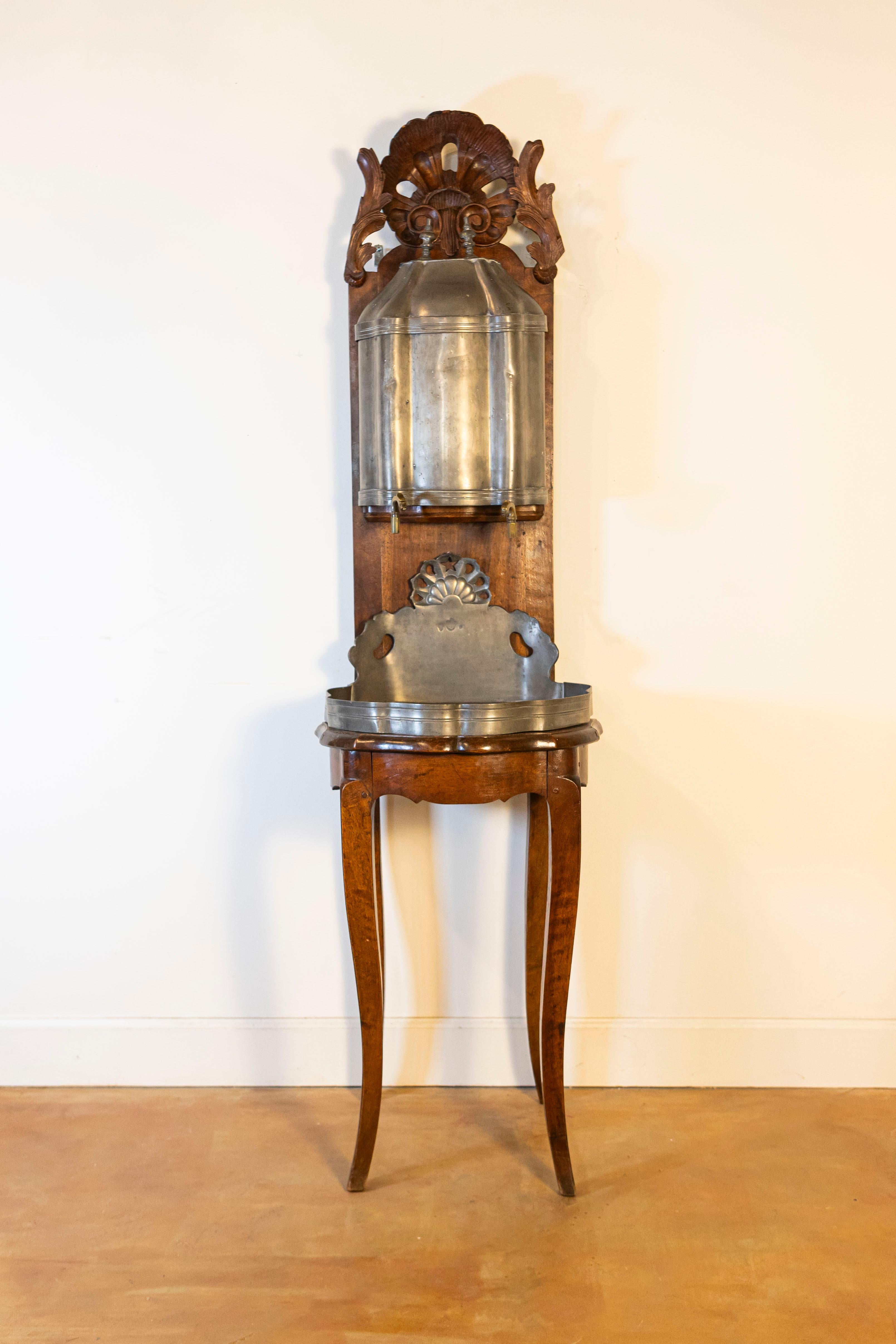 A French Louis XV period pewter lavabo on hand-carved walnut stand from the late 18th century, with shell motifs and acanthus leaves. Created in France at the end of the reign of king Louis XV nicknamed 