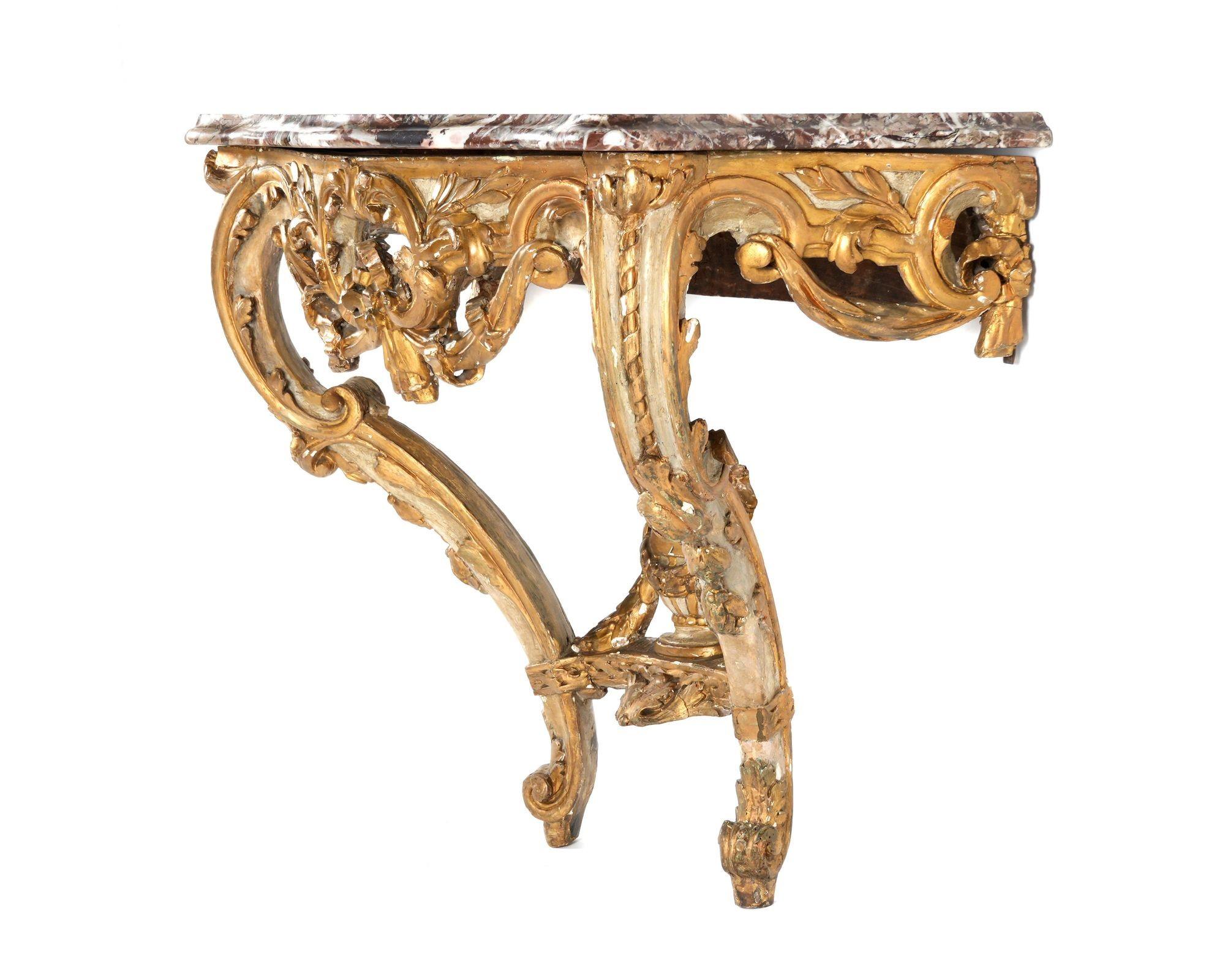 Palatial Louis XV style hand carved gilt-wood console made in France, Late 18th Century, having a veined marble top in alluring red and white tones. The gilt-wood work is adorned with delicate hand-carved botanical figures.
A notable centerpiece of