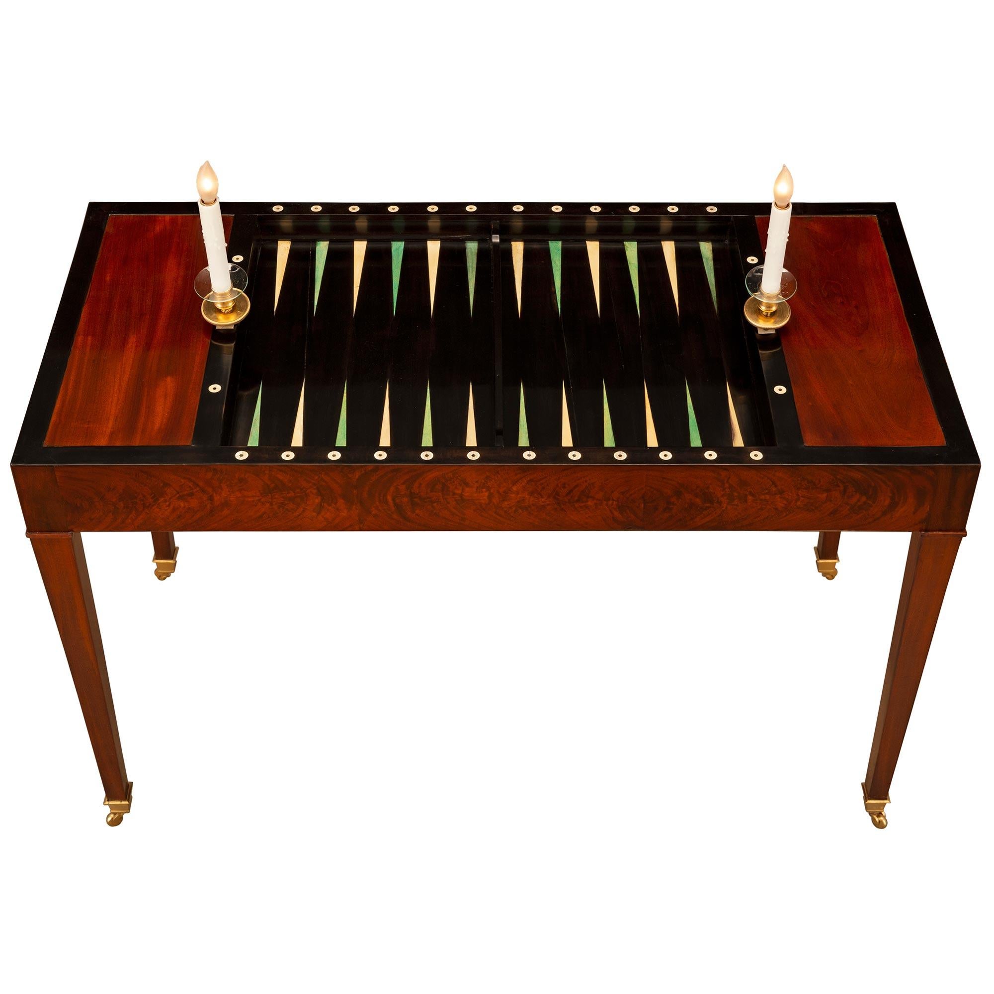 Preciosa y elegantísima mesa de juegos Tric Trac electrificada de caoba y ormolina del periodo Luis XVI francés de finales del siglo XVIII. La mesa rectangular se eleva sobre patas cónicas cuadradas con sus ruedas originales de ormolu. El friso