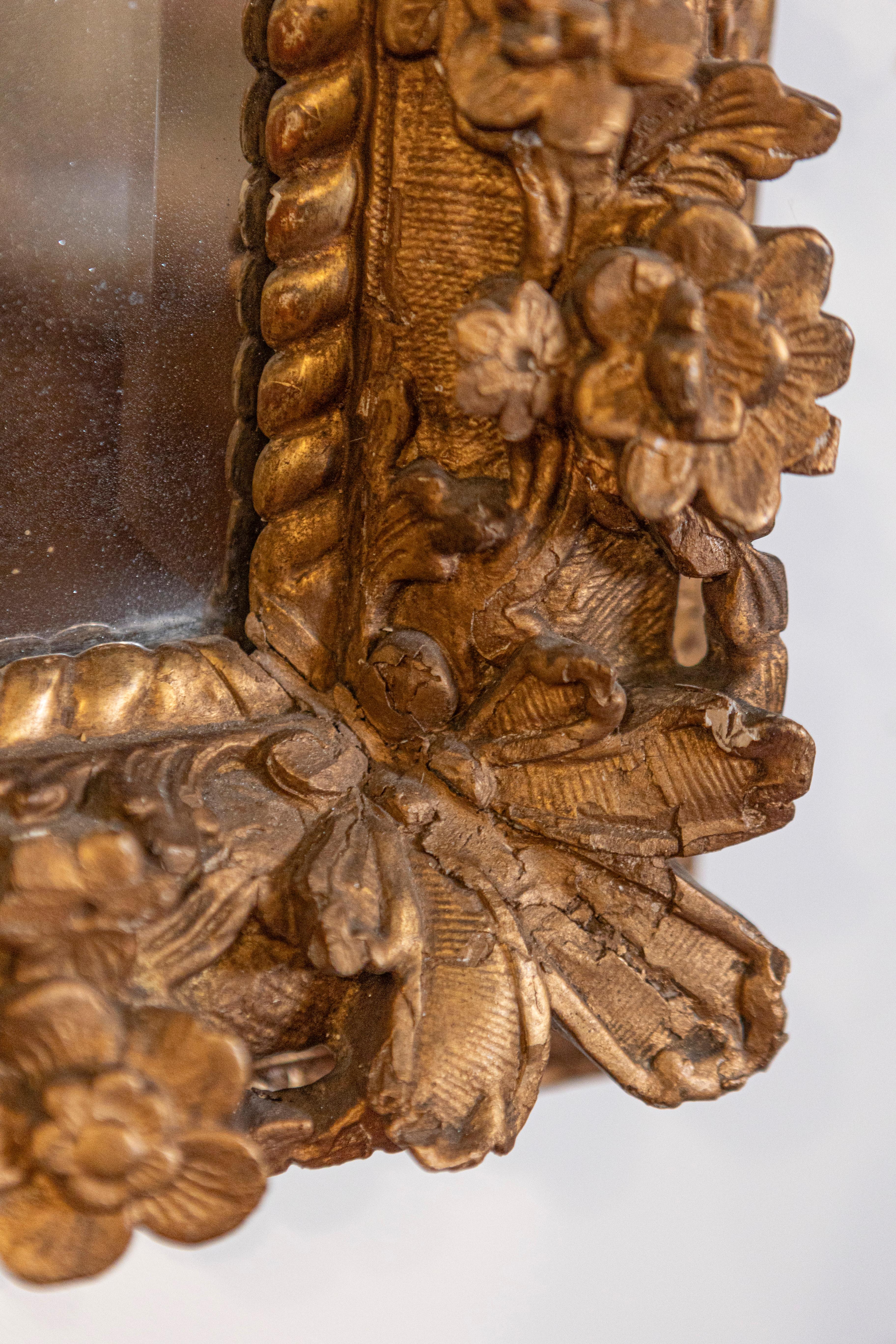 Dieser französische Schnitzspiegel im Régence-Stil aus dem späten 18. Jahrhundert hat einen exquisiten rechteckigen Rahmen aus vergoldetem Holz, der an den Ecken mit zarten Blumenmotiven verziert ist. Die Qualität der Schnitzerei ist unbestreitbar.
