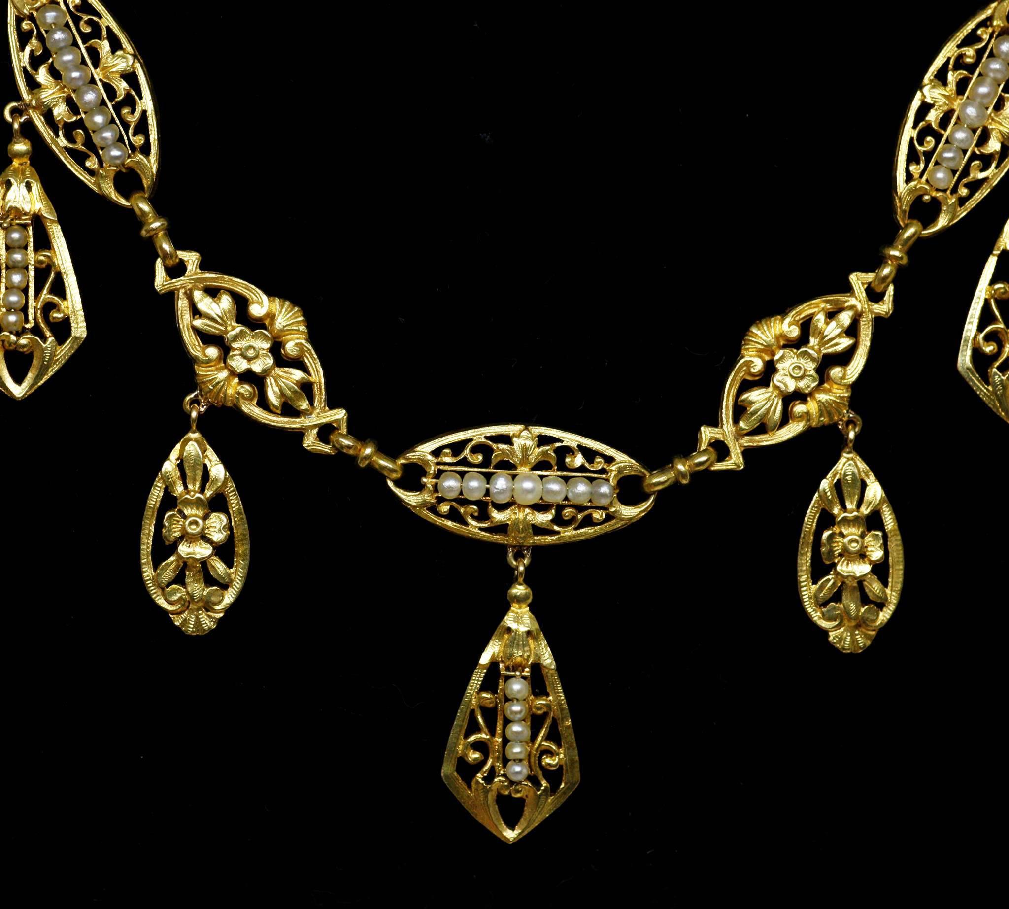 Antique yellow 18k gold necklace of a rare model with 7 pendants. Each link is decorated with a floral pattern and 6 of them are enhanced with small natural pearls. 
Perfect condition.
French (hallmark : eagle’s head), circa 1880

Length : 46 cms