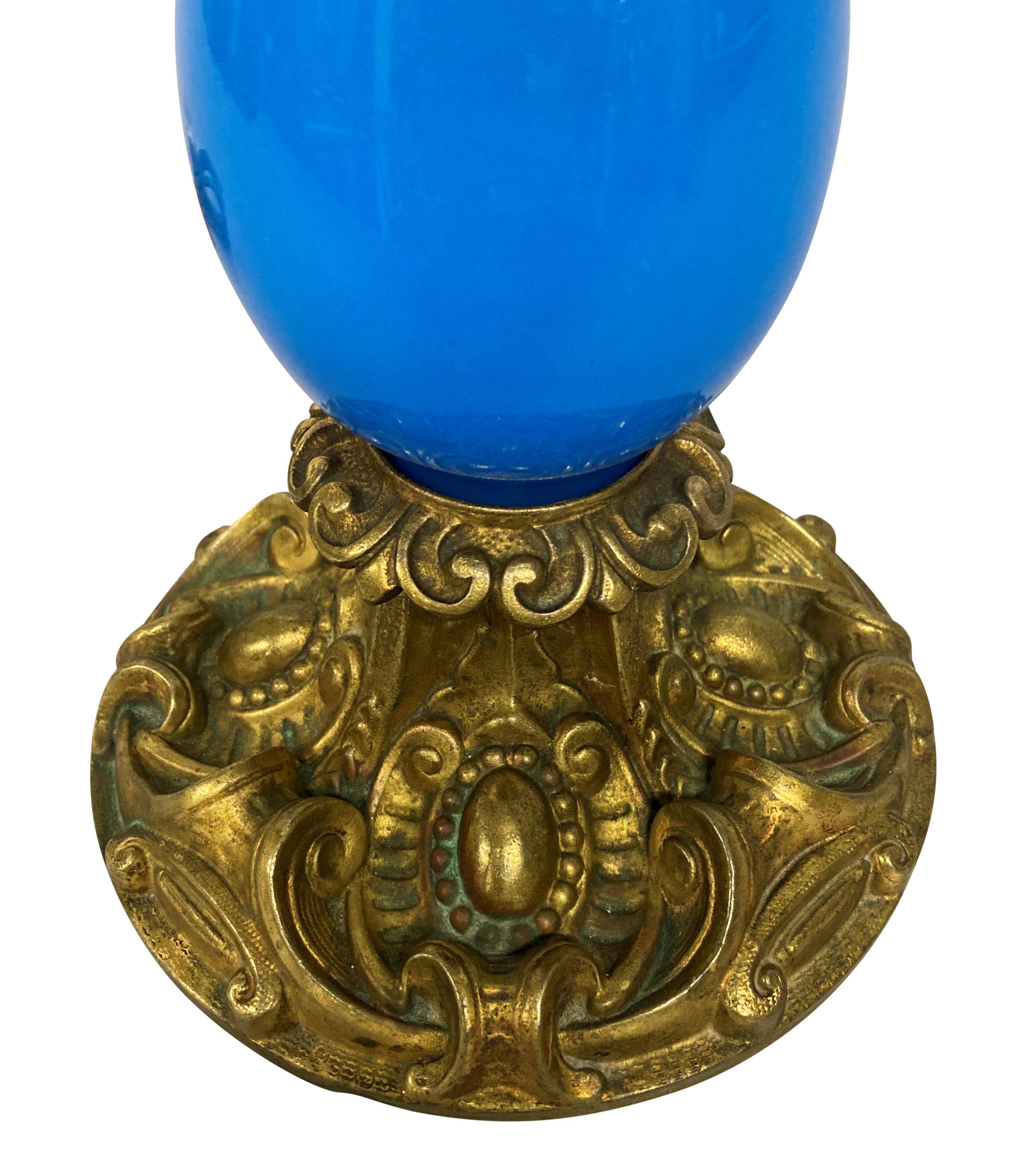 A French late XIX Century blue glass table lamp, with gilt metal decorative mounts. Formerly for oil.