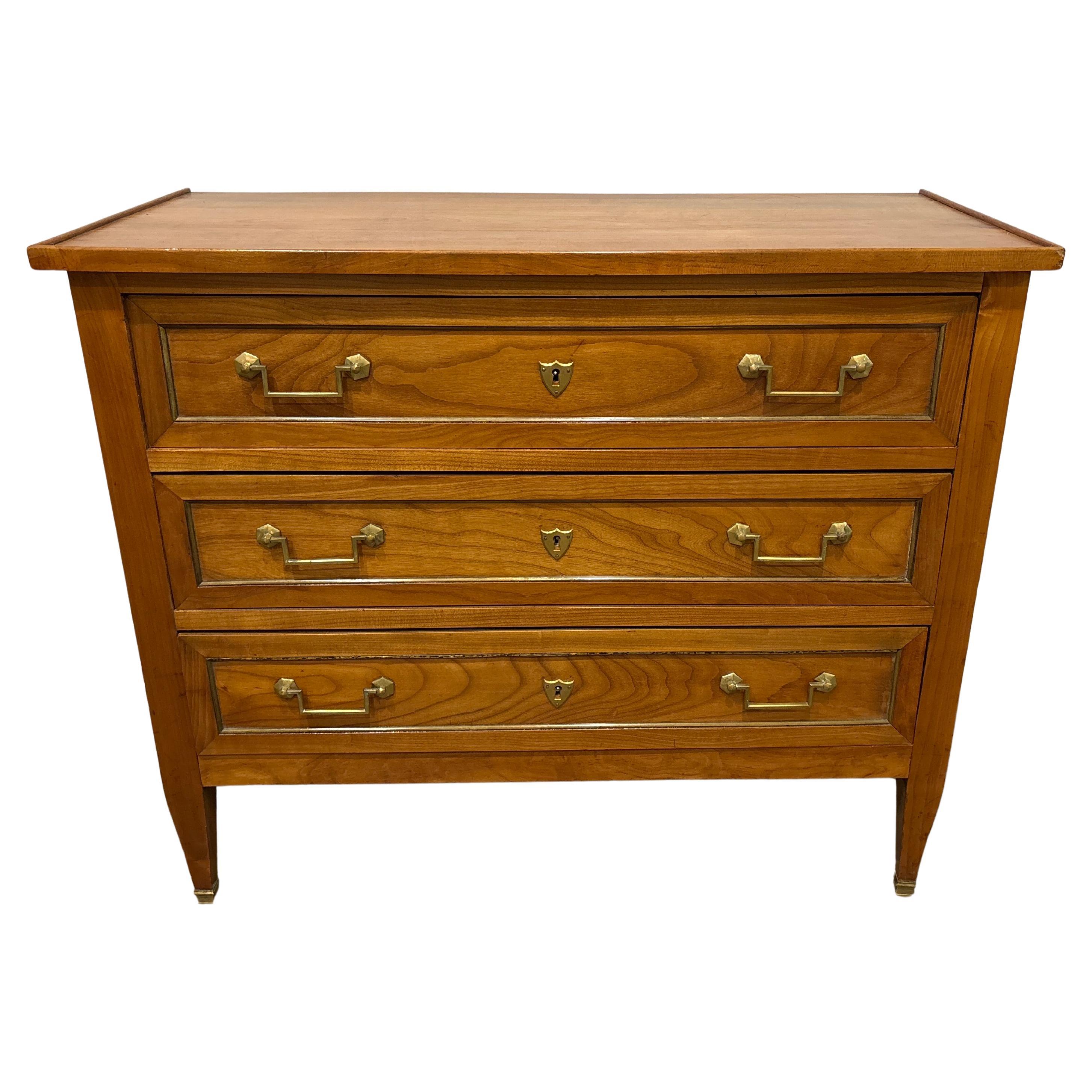 This charming commode is made of fruitwood in the Louis XVI style. It has a wood top with a frame around.