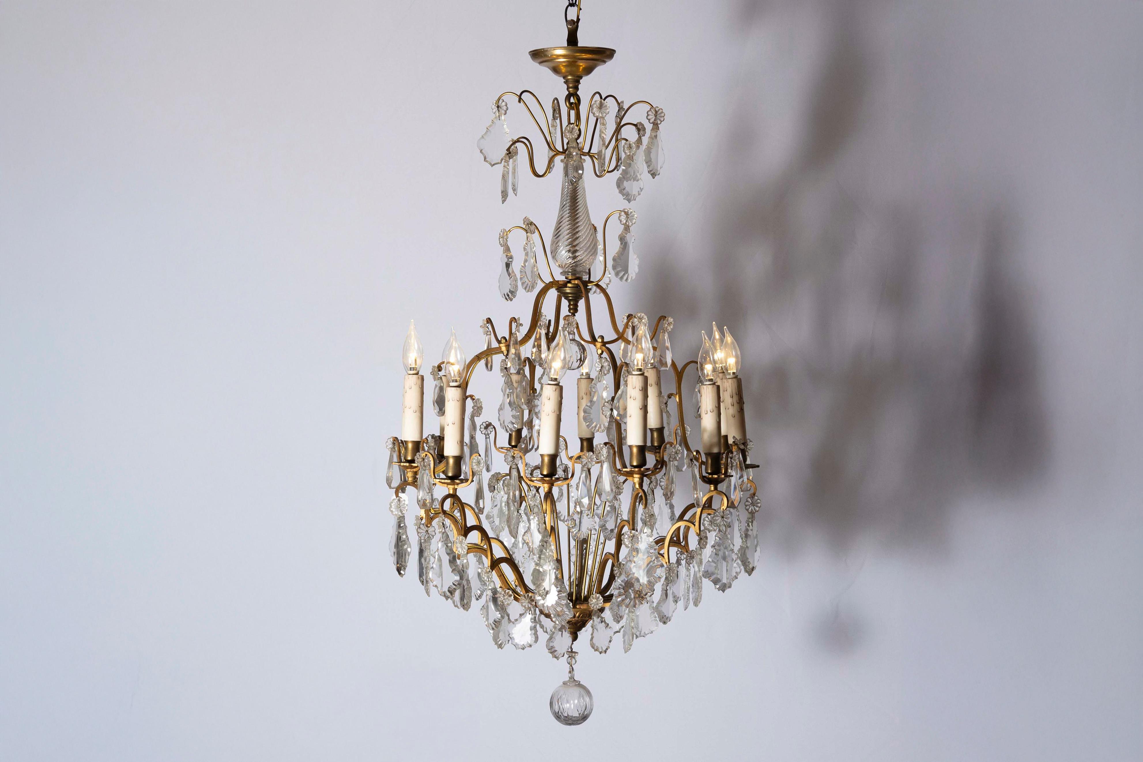 A French 12-light crystal chandelier from the late 19th century, with brass armature and pendeloques. Born in France during the last quarter of the 19th century, this exquisite 12-light chandelier features a central crystal baluster motif with