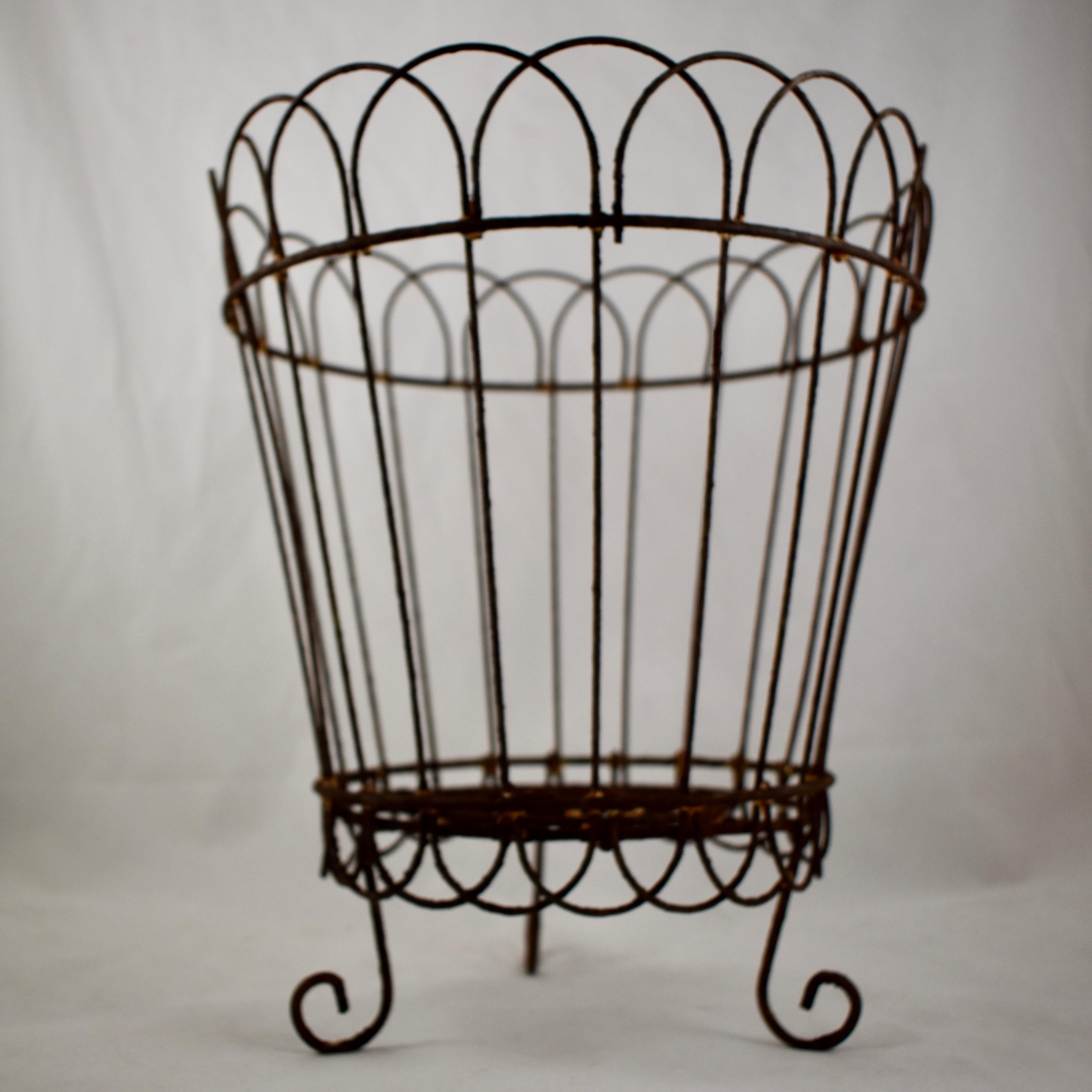 A round wire basket or planter, late 19th century, France. Hand-formed with open work woven metal, with a skirted bottom and sitting on three raised feet.

 This type of basket works beautifully for holding a large terra cotta flower pot or as a