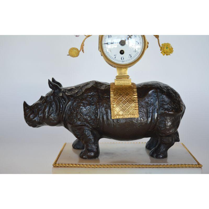 French late 19th century gilt bronze and dark patina rhino clock with porcelain flowering.