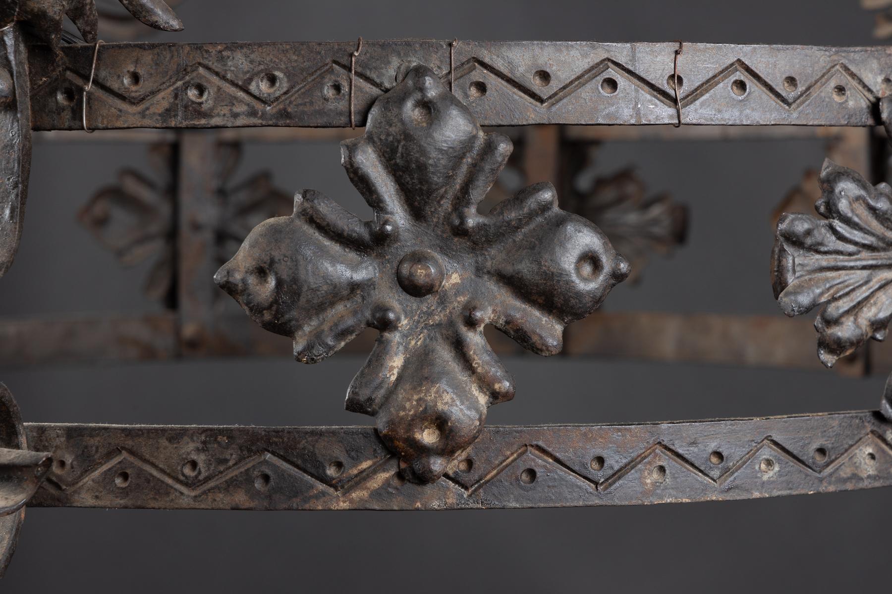 French late 19th century Gothic Revival iron chandelier made for electricity – we can tell since the bulbs are pointing down, to show the novelty of the electric light.  Each arm is a winged dragon joined to the center, holding a ring in its mouth