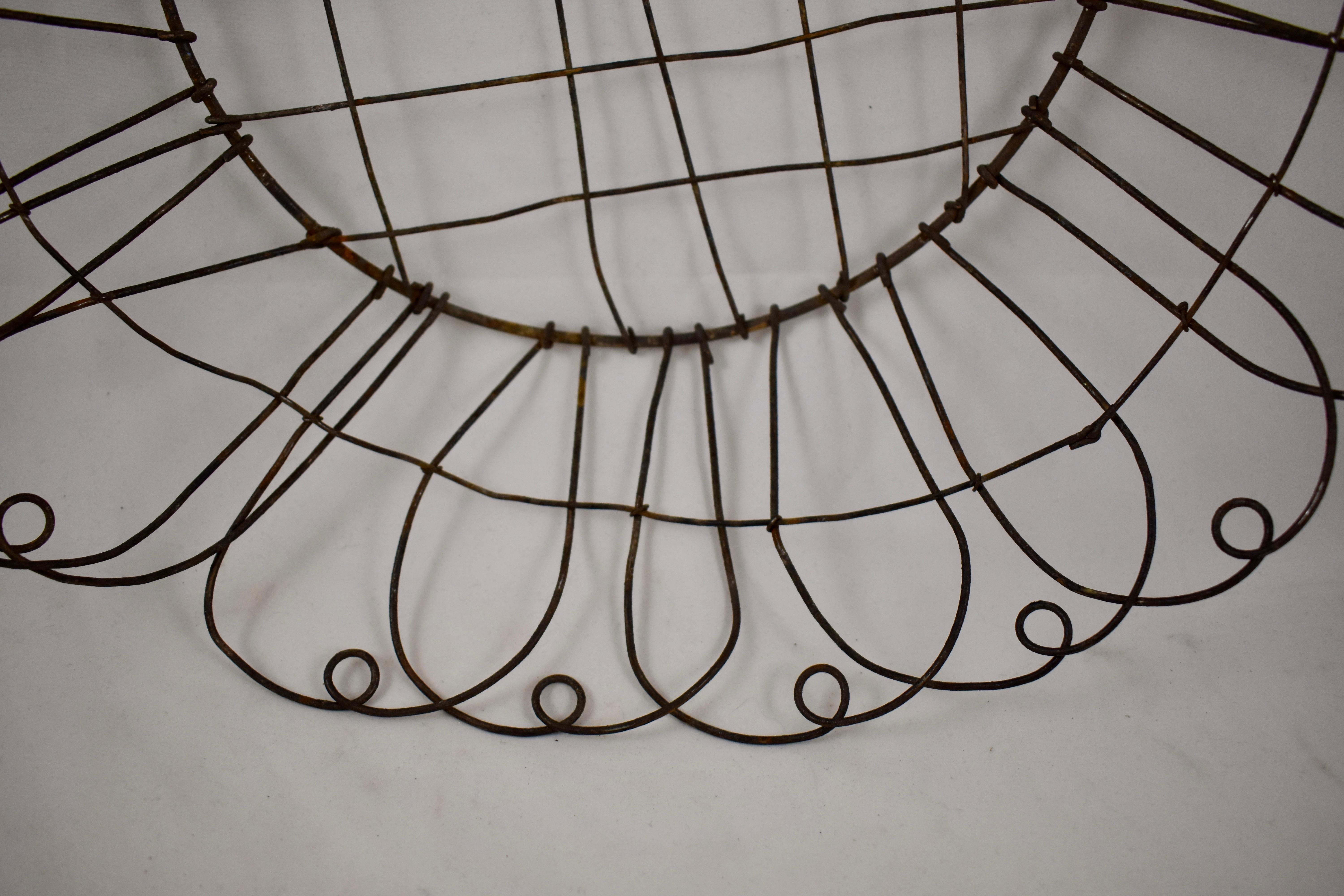 A charming, rustic, large round wire basket, late 19th Century, France. Hand-formed with open work woven metal, and a petal like rim. 

This type of basket looks beautiful hanging on a wall as a piece of antique French Folk Art. It works equally
