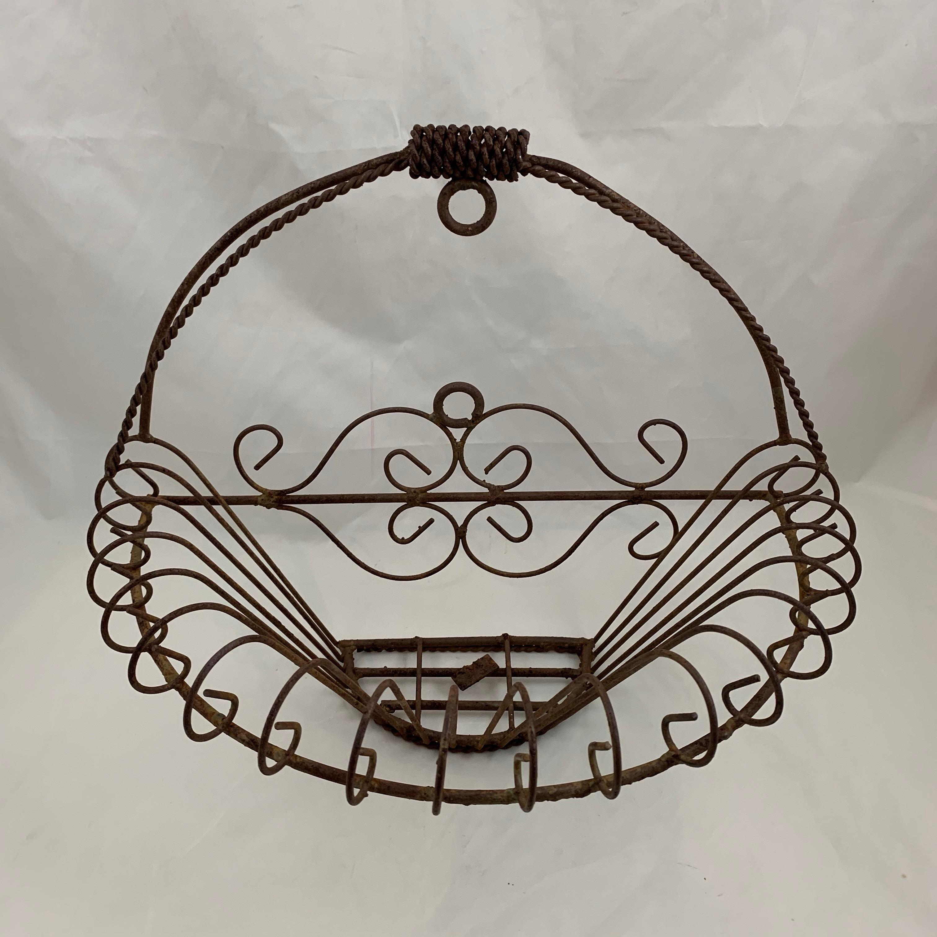 A half-round, flat back iron basket form jardinière, late 19th century, France. Hand-formed with open work metal and a scrolled rim. This basket sits upright on its own or it can hang flat on a wall. A twisted wire top handle with a hanging ring and