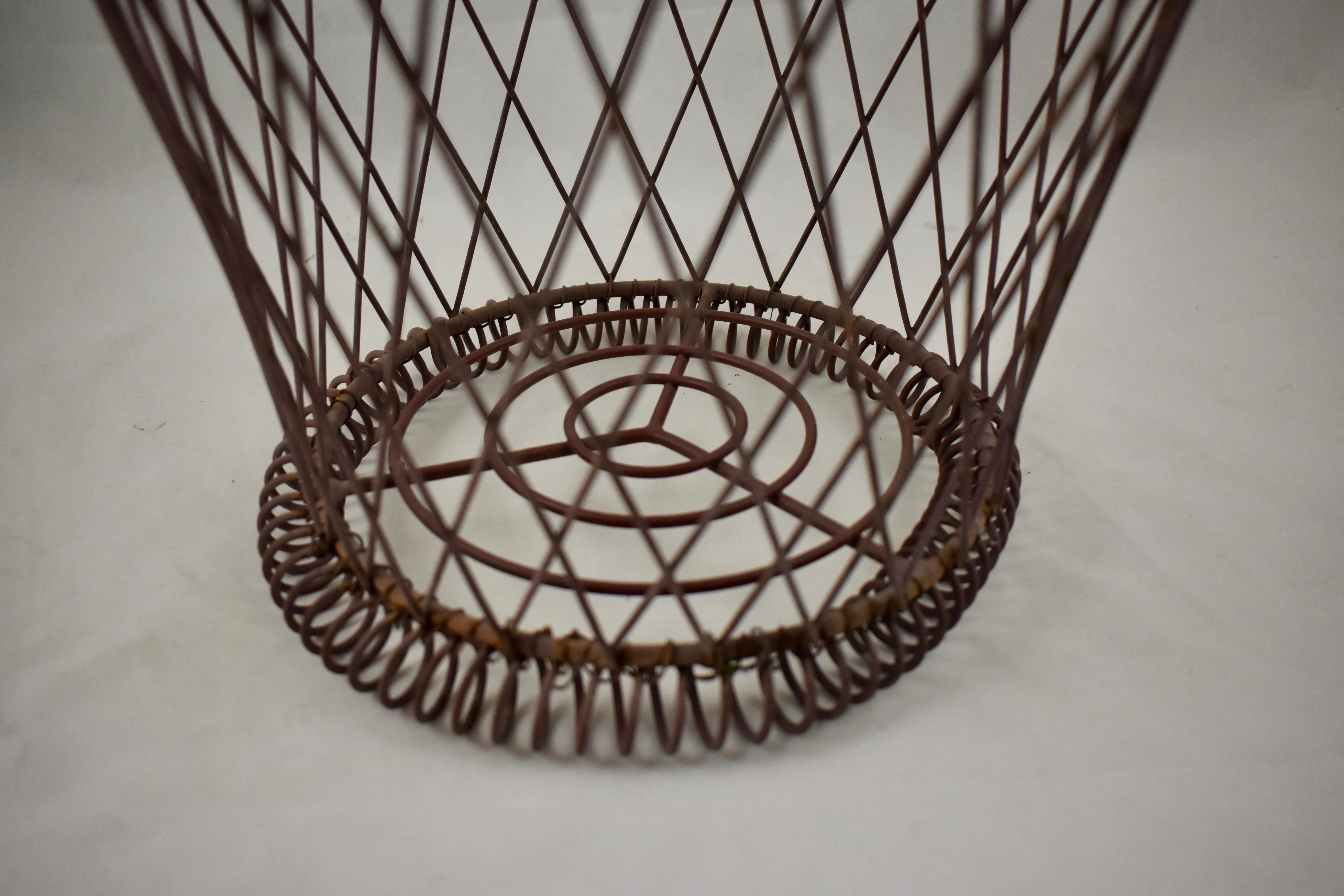 A round wire basket, late 19th century, France.
 
Hand-formed with open work metal woven with a scrolled bottom, this type of basket works beautifully for holding a large terra cotta flower pot or as a waste basket in a bath or bedroom. With the