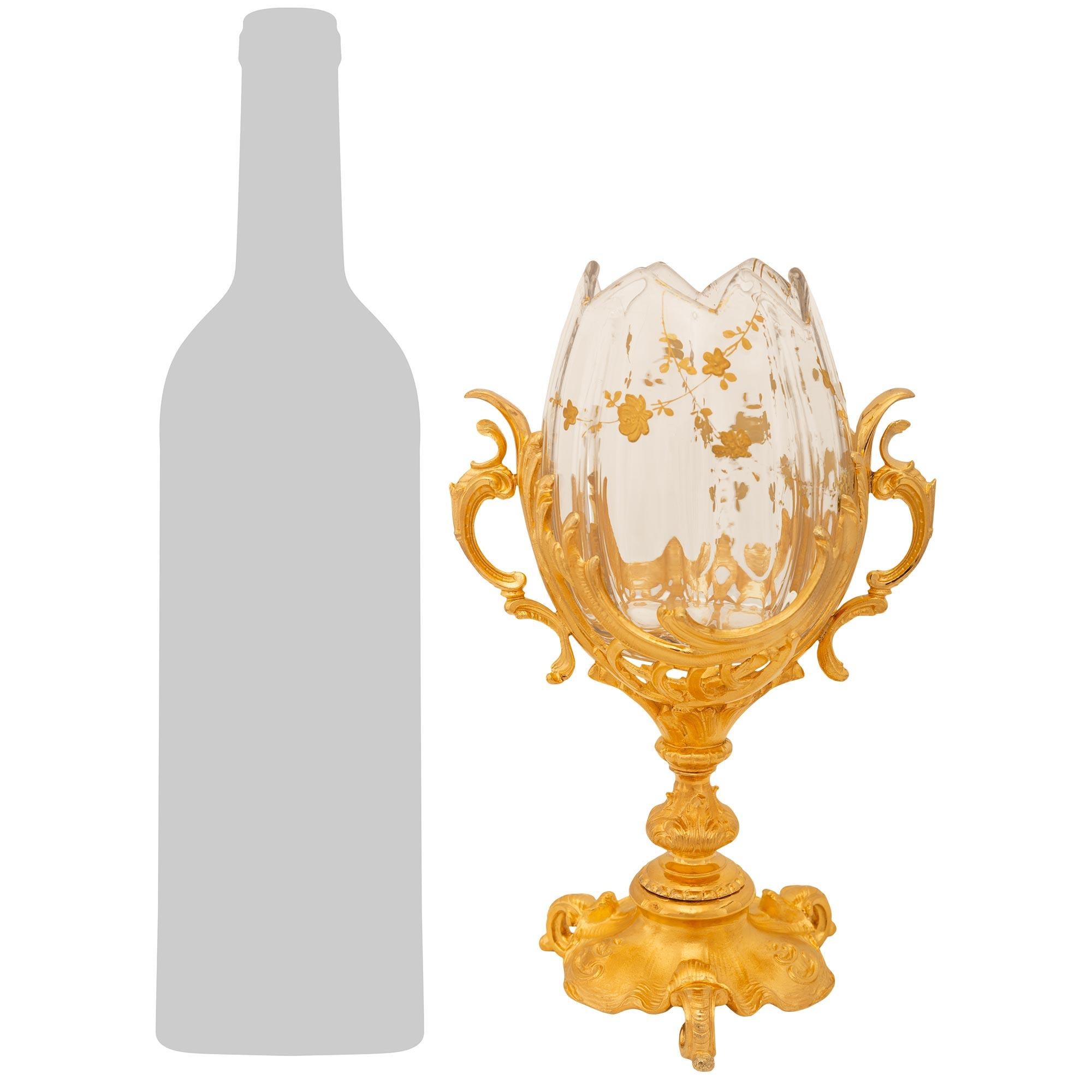Un grazioso e decoratissimo vaso francese della fine del XIX secolo in stile Luigi XV con ormolu e cristallo Baccarat. Questo vaso unico nel suo genere poggia su una base a forma di ninfea sostenuta da tre piedini a forma di 