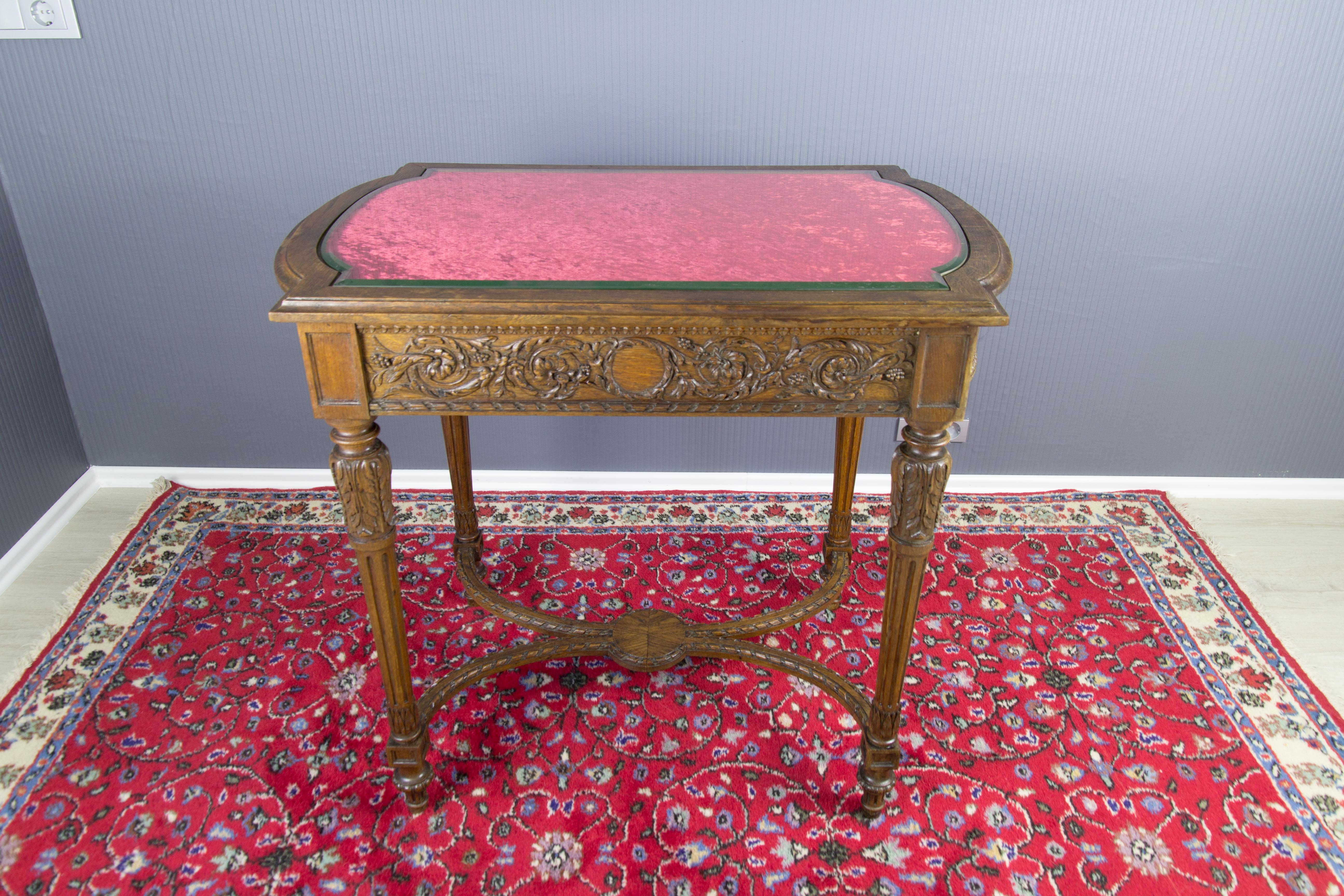 French late 19th century Louis XVI style center table.
A beautiful Louis XVI-style center table made of walnut wood with delicate floral and leaf carvings. The beveled glass top and burgundy fabric under it are shaped to fit the walnut top base. In