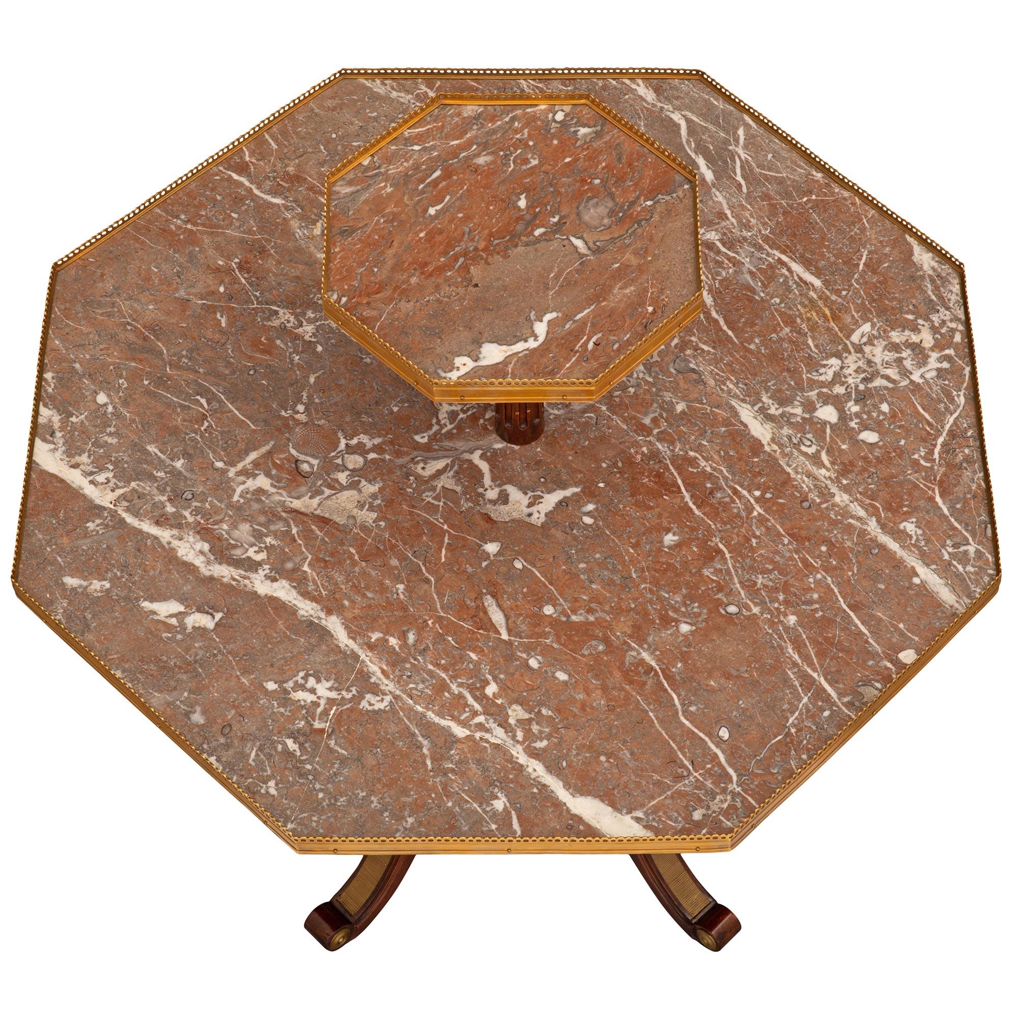 A uniquely shaped and most attractive French 19th century Louis XVI st. Mahogany, ormolu, and Coquillier de Bilbao marble table. The octagonal two tiered table is raised by four elegant scrolled legs with fine mottled ormolu cabochons and fitted
