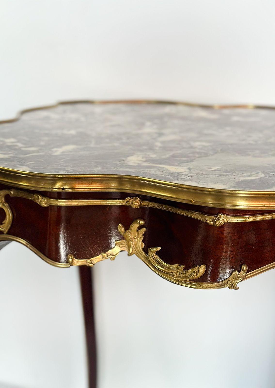 Majestic wood side or occasional table made in France in the Late 19th Century, consisting of a beautiful purple breccia marble top with a unique figure and figural bronze foliate motif and portrait mounts surrounding the piece. The table also