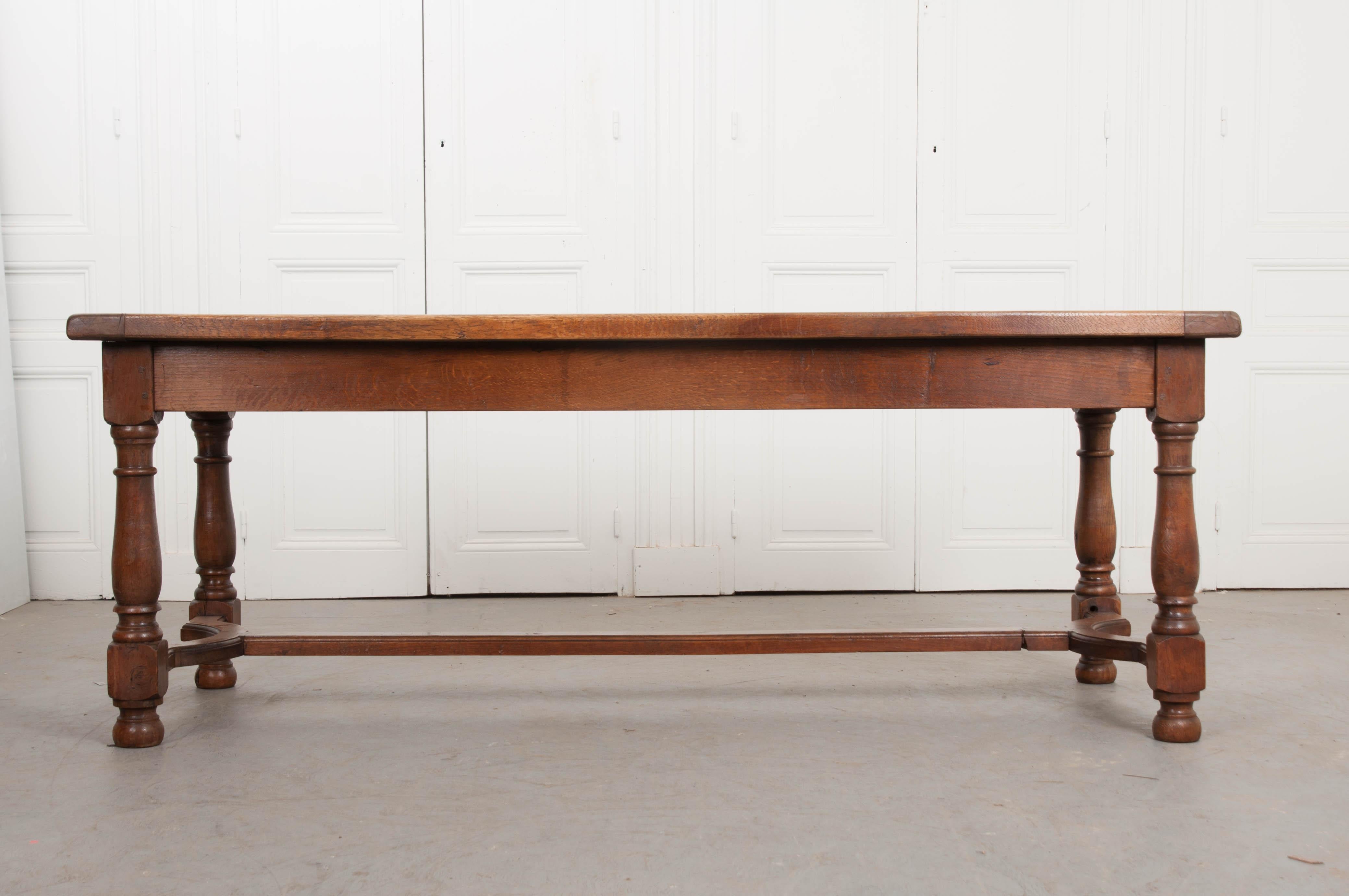 This beautiful oak farmhouse table, from late-19th century, France, features a top constructed of a single parquetry-inlaid panel with breadboards, over an apron with drawers, having cast iron ring pulls, on each end perfect for flatware and linen