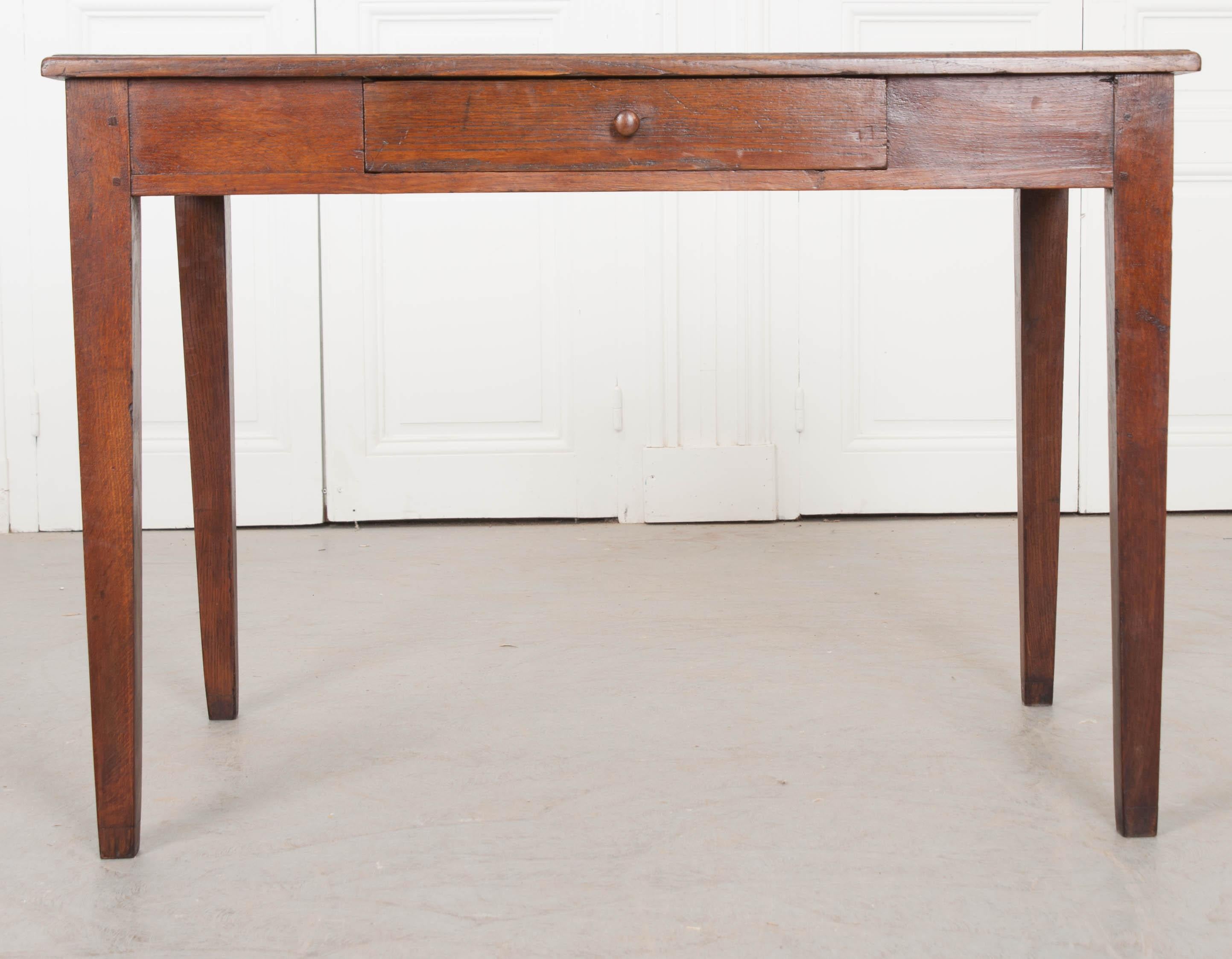 An unpretentious oak writing desk, made in France at the end of the 19th century, circa 1890. The solid wood desk has a restrained designed that is simply beautiful. A single drawer can be found in the apron that can be accessed with a pull of its