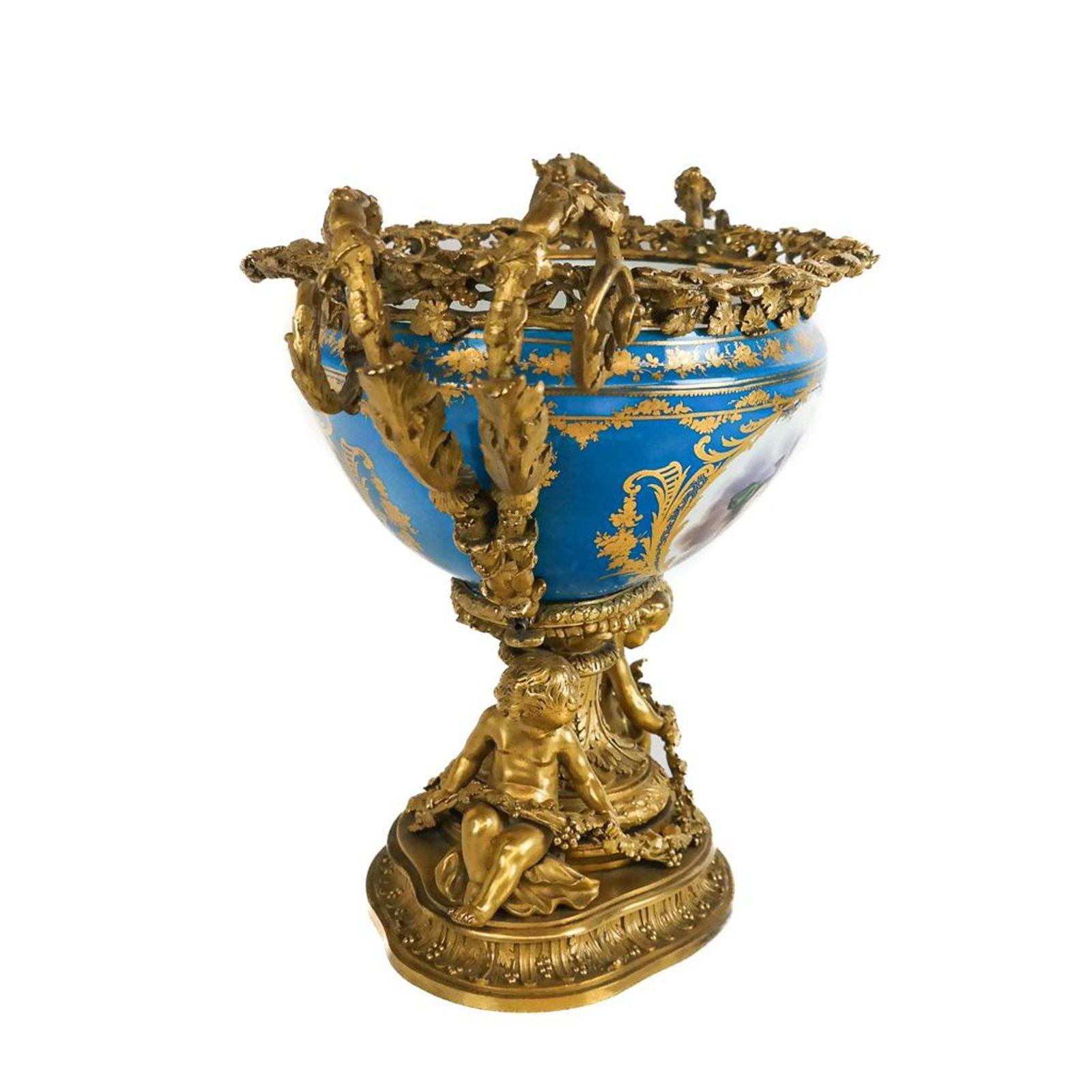 Graceful porcelain and gilt bronze centerpiece made in France in the late 19th century, featuring colorful floral scenes painted on the porcelain, capturing the beauty of nature. Adding to its charm, three cherubs are depicted in the porcelain,