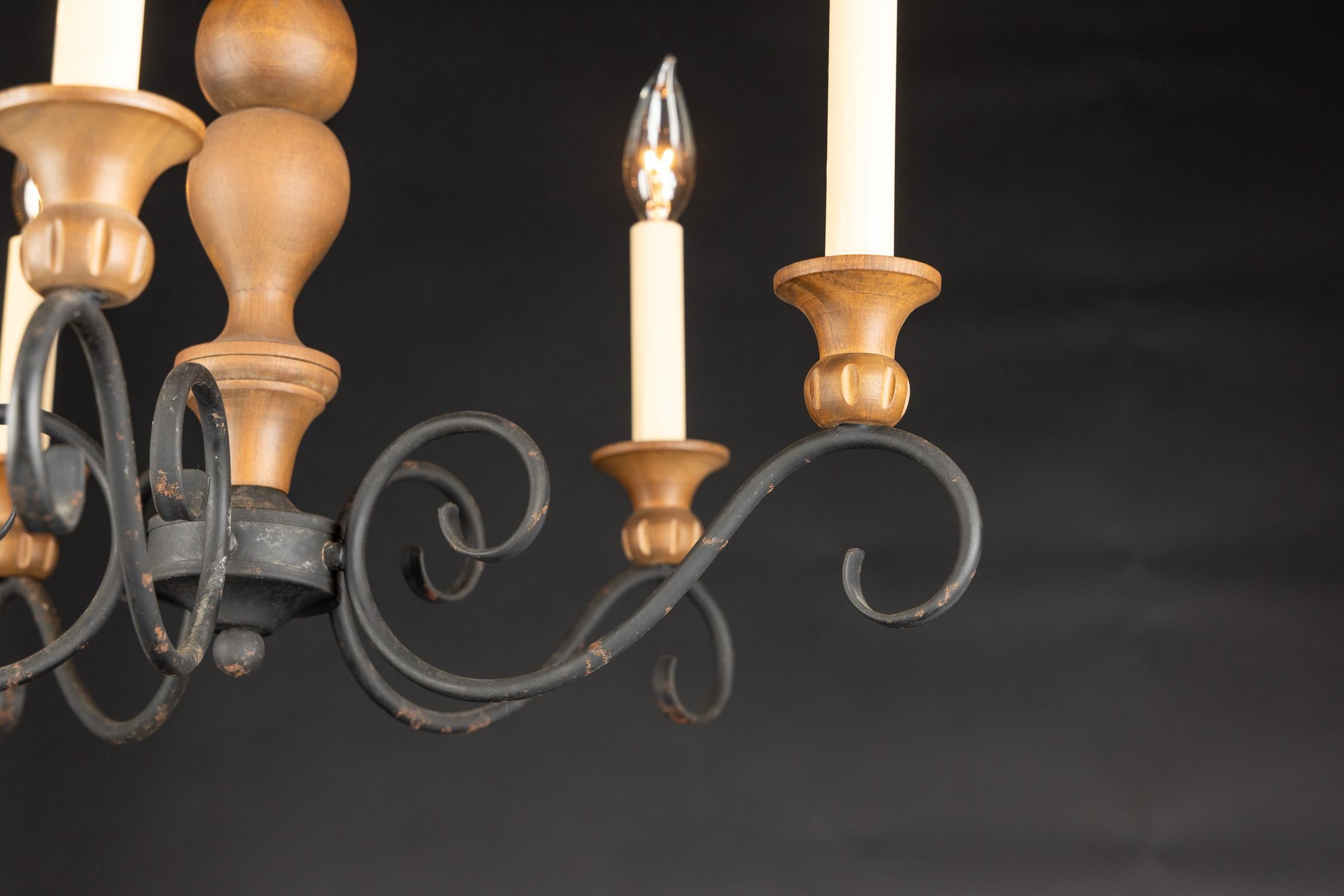 Unusual French late 19th century Louis XV country chandelier with iron scroll arms, carved wood candle cups, and a solid wood center, suspended by an iron hook at top.

Each piece in our shop is professionally rewired and in working order. They have