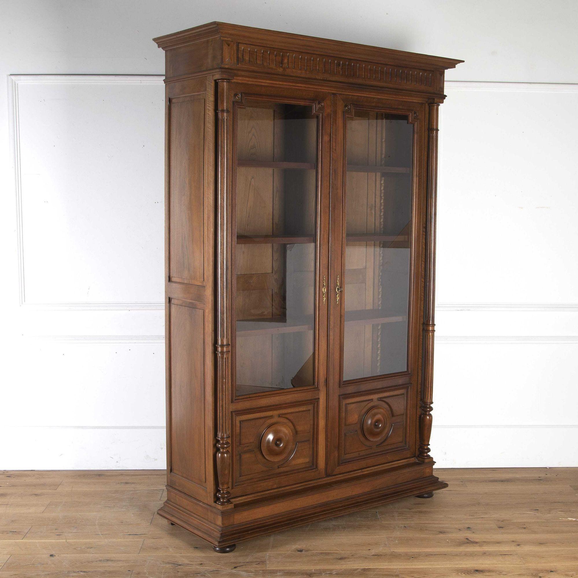 Very fine quality late 19th Century French solid walnut bookcase. Circa 1880s. 
This bookcase has a projecting moulded cornice which sits above a reeded frieze. 
The twin glazed doors, with re-entrant corners, enclose an arrangement of four later