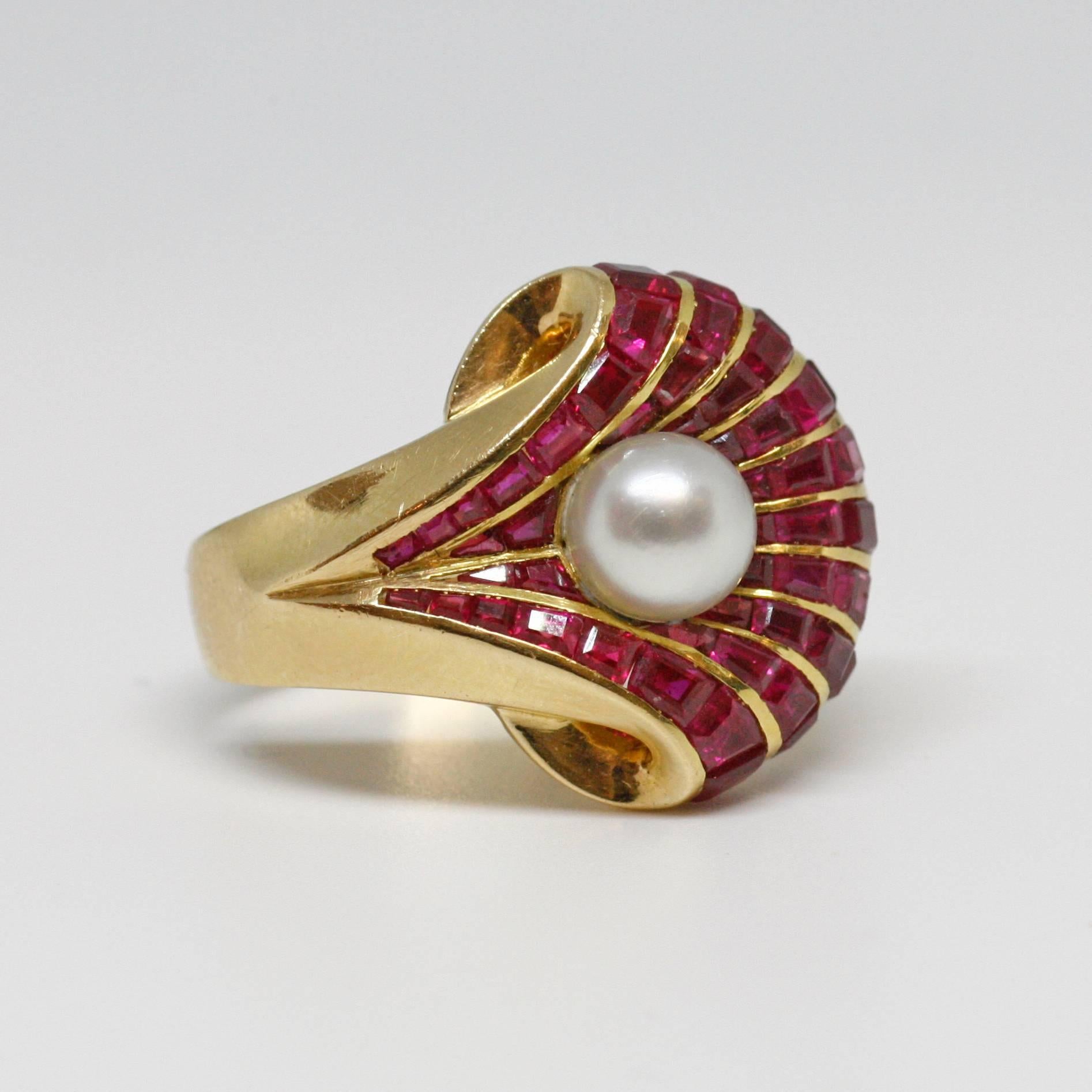 Rare cocktail ring with a very interesting design. This ring is made in 18k gold (slightly pinkish color) and set with calibré-cut rubies (raspberry color, probably of Burmese origine) and a central cultural pearl (diameter 6.9 mms).
Tiny chip on