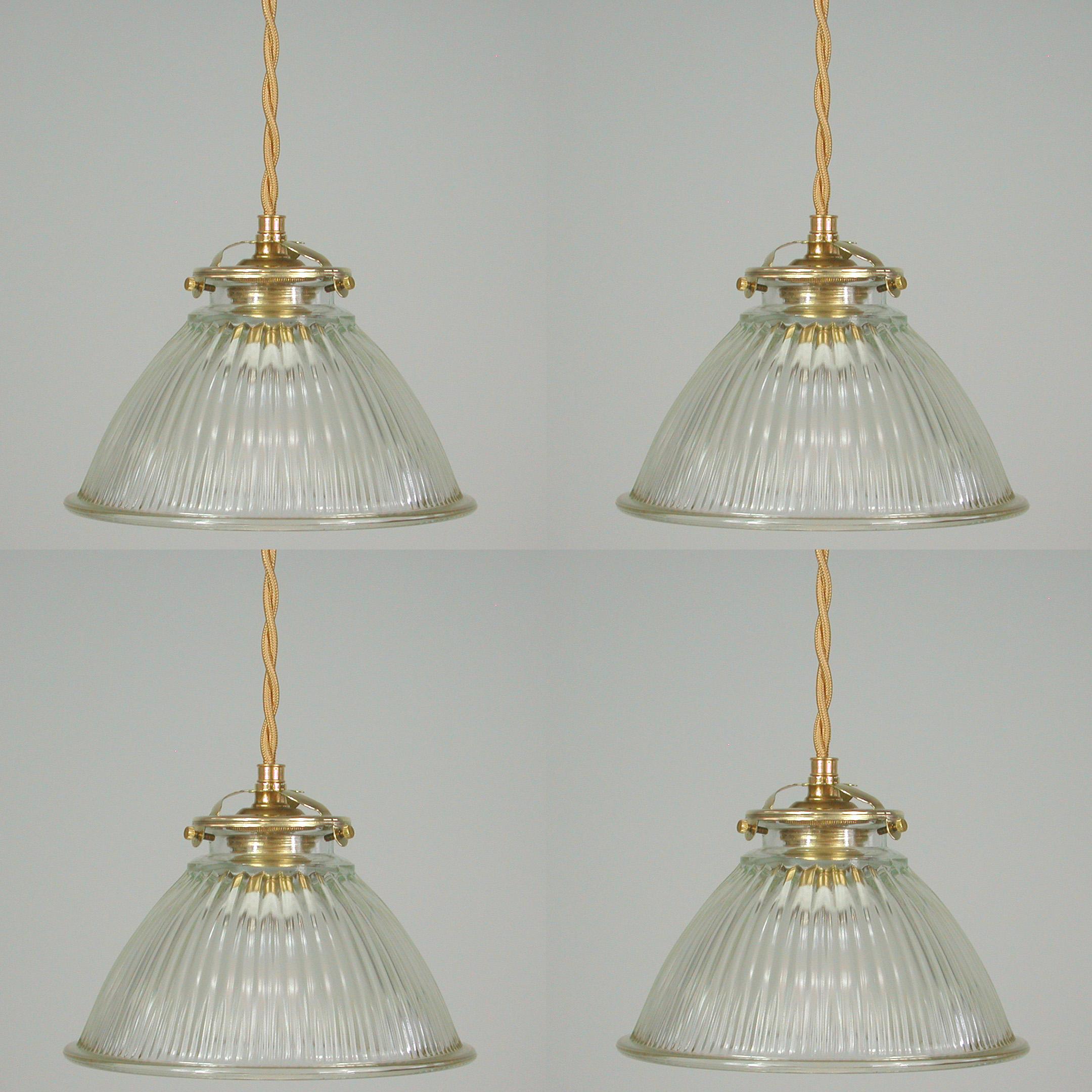 These Art Deco dome shaped pendant lights were made in France in the 1930s to 1940s. They feature a clear prismatic glass Holophane lamp shade and brass glass holder with gold colored fabric wiring.

The glass gives off the best quality light. It
