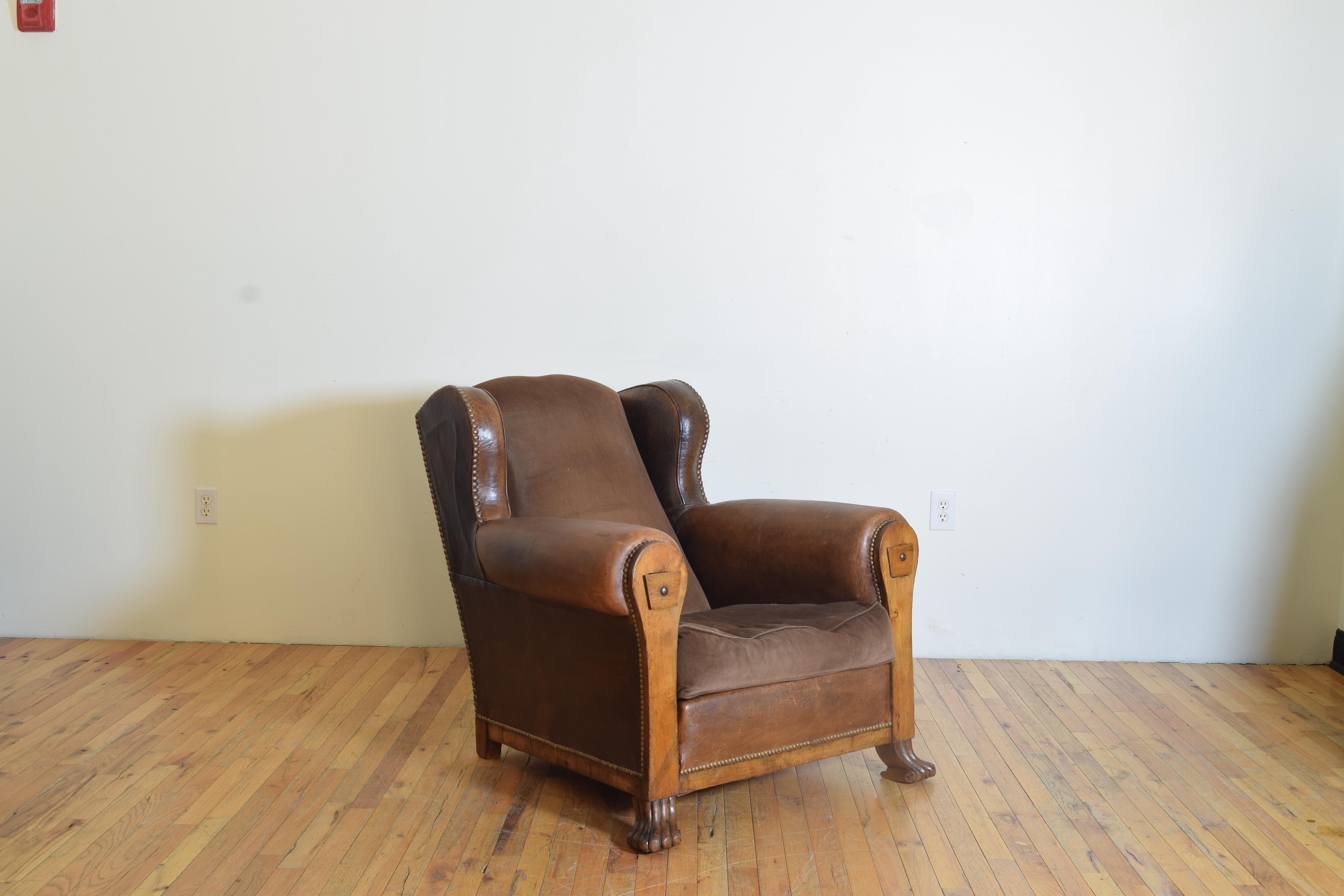 This handsome and comfortable club chair has a generous lean and velvet seat and back, the overall frame upholstered in its original leather with patinated brass nailhead trim, the front of the chair with oak panels containing two drawers,
