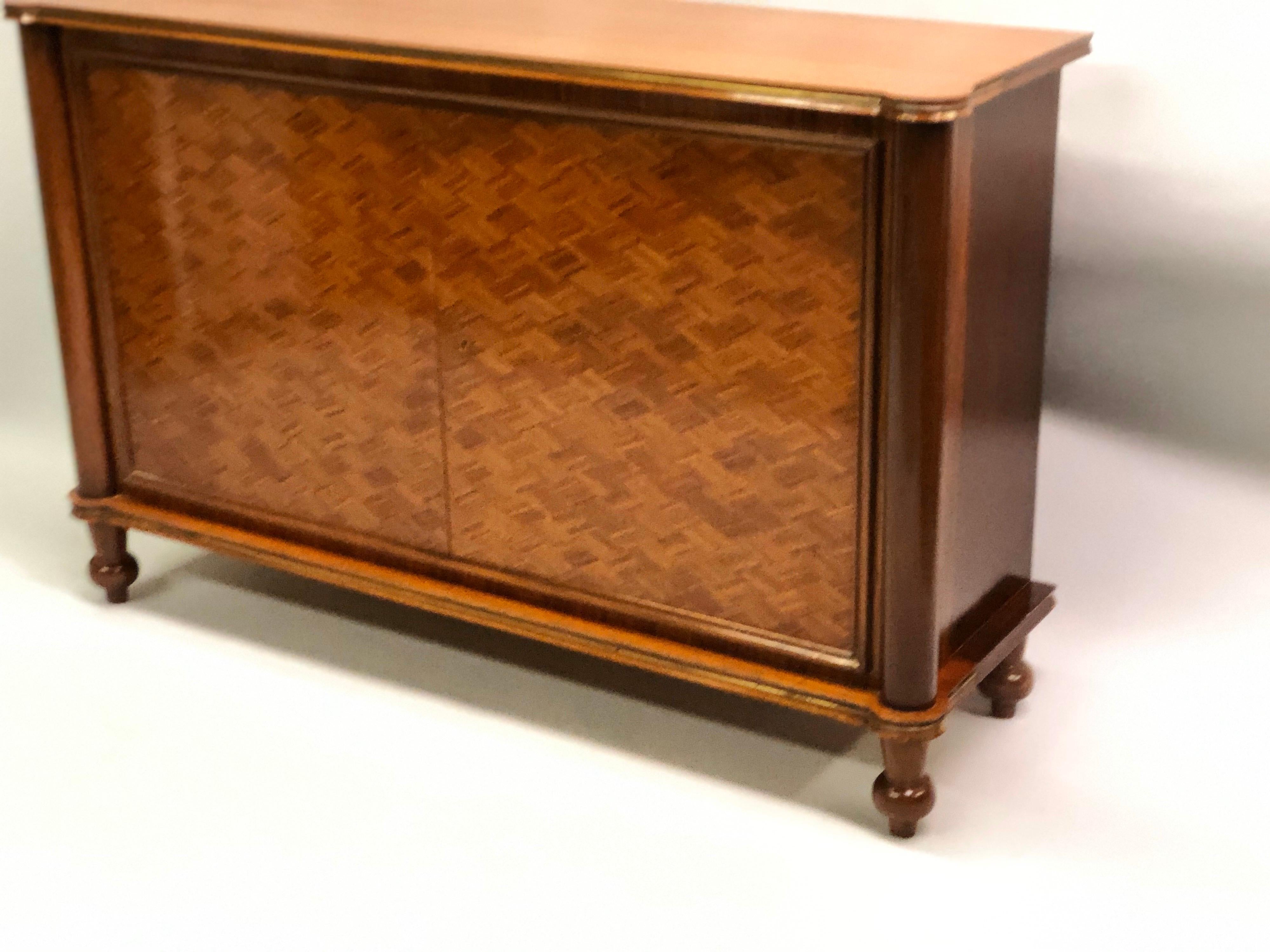 Elegant French late Art Deco / modern neoclassical sideboard / buffet by Jules Leleu,

A 2-door cabinet composed in mahogany with the doors in a herringbone wood inlay and inset brass details along the upper and lower borders of the entire piece.