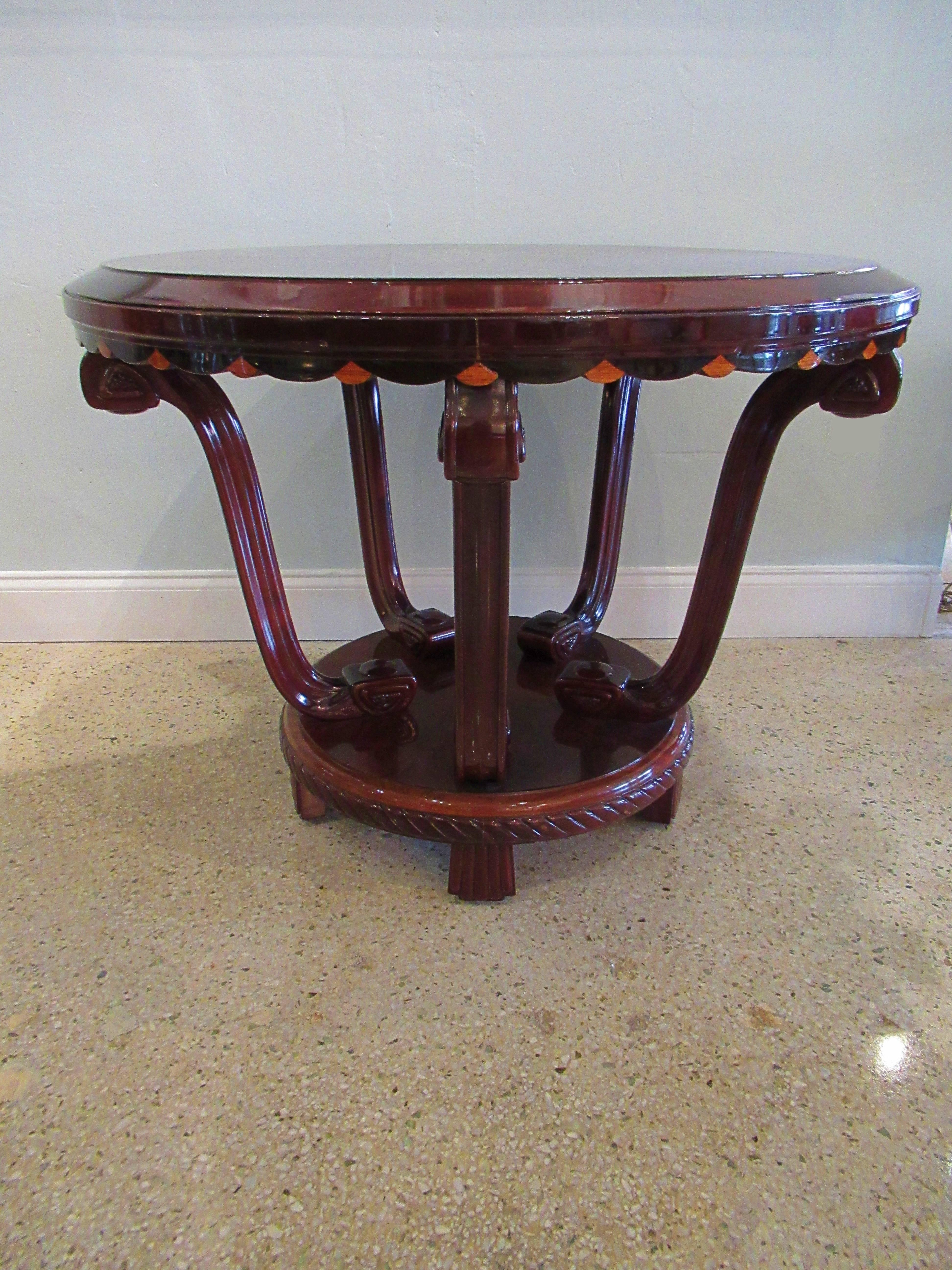 The circular top with spectacular radial veneer, the frieze with scalloped edge inlaid with lemonwood lozenge, on four curved and carved legs, meeting on a central circular base, radially veneered with a circle in the center, the frieze of the base