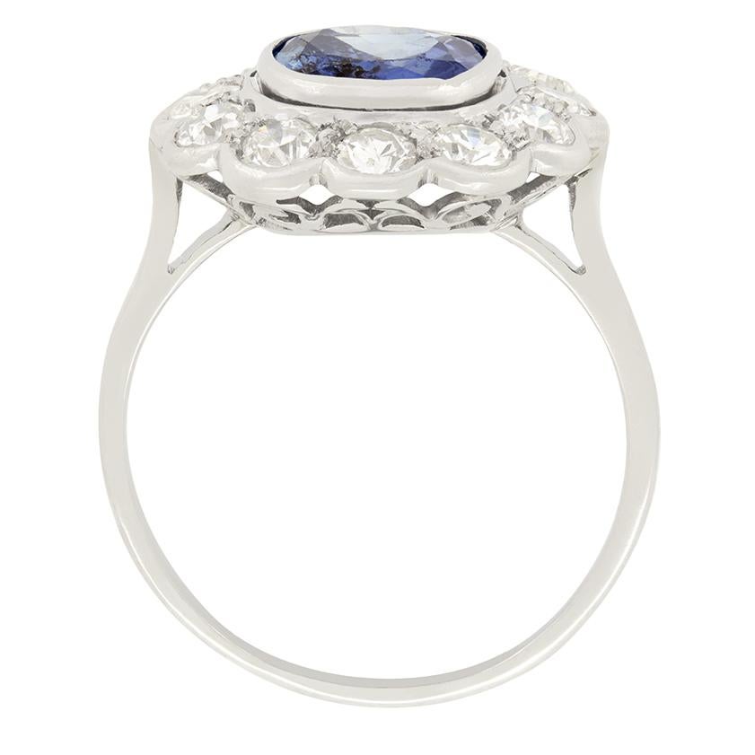 A bright and desirable cornflour blue sapphire takes centre stage in this Late Deco cluster ring. The sapphire has a substantial weight of 2.40 carat and despite the visible inclusion, it is an incredibly lively stone. It is surrounded by a halo of