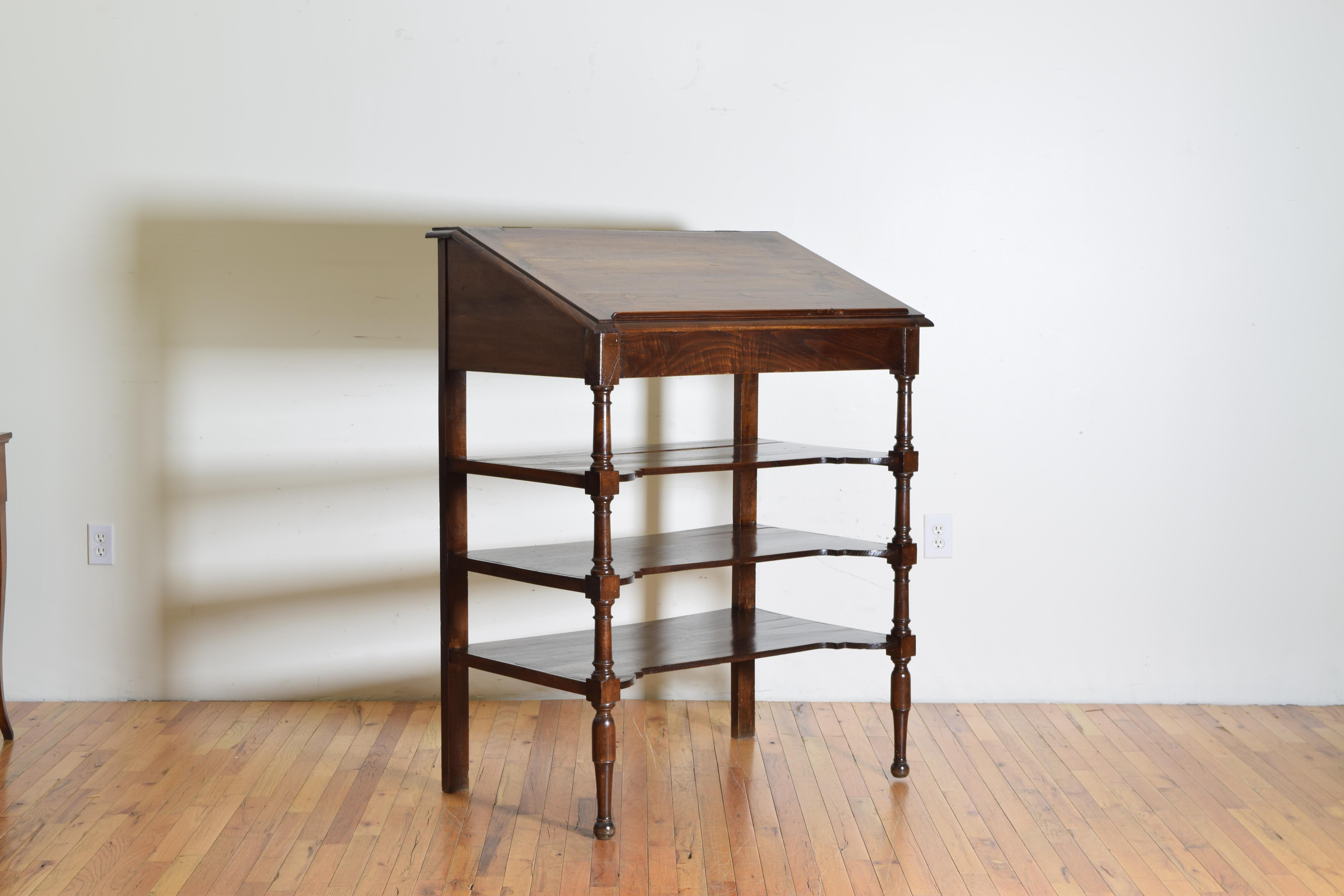 The upper slanted section with a raised bookrest has a hinge opening to a reveal a storage well, with three shaped shelves connecting turned front legs and block rear legs, early third quarter of the 19th century.