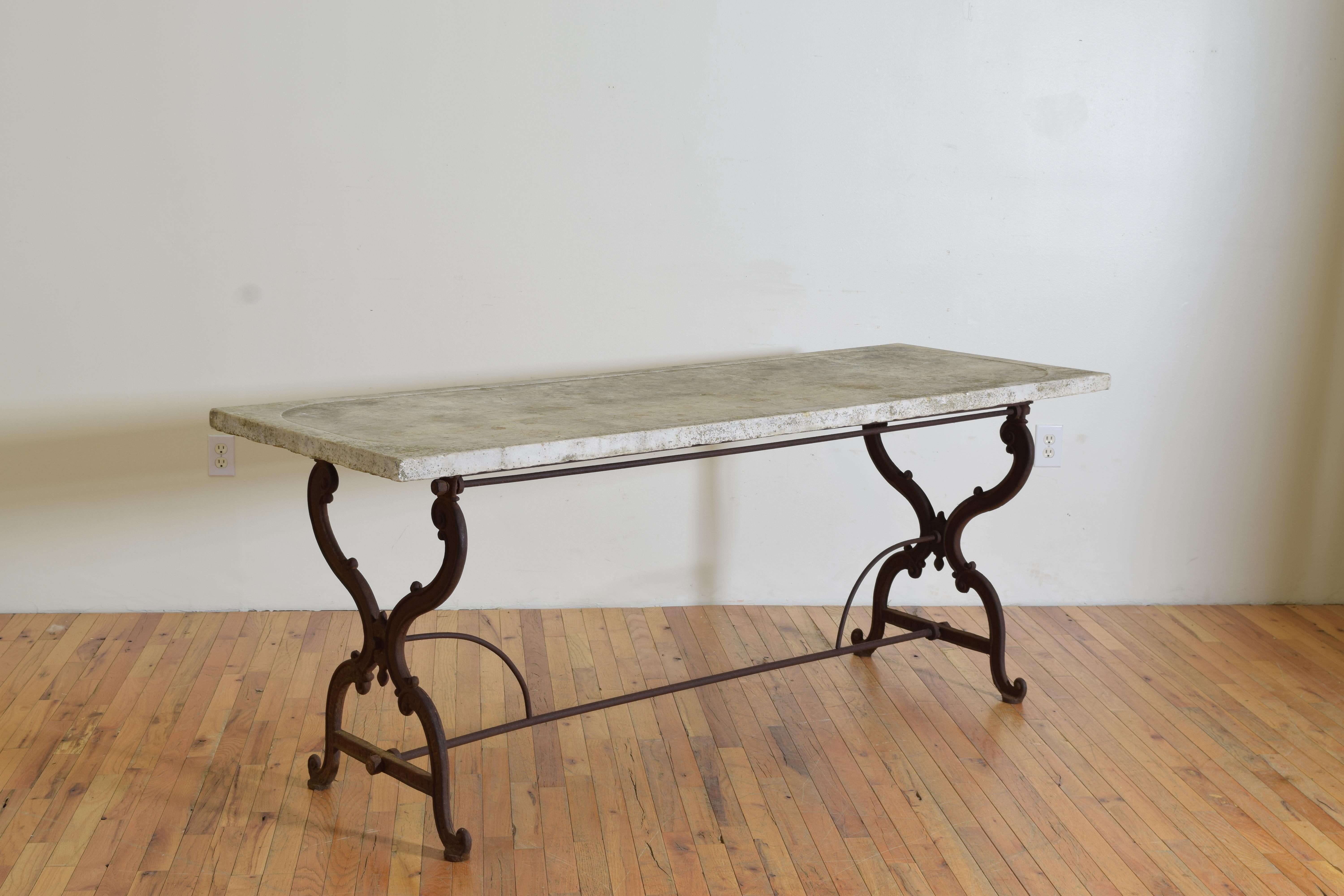 Having a very thick rectangular marble top with a slightly sunken center and drain hole at middle, the top resting on a wrought iron base with scrolled x-form supports joined by a solid round bar elongated h-form stretcher with additional curved