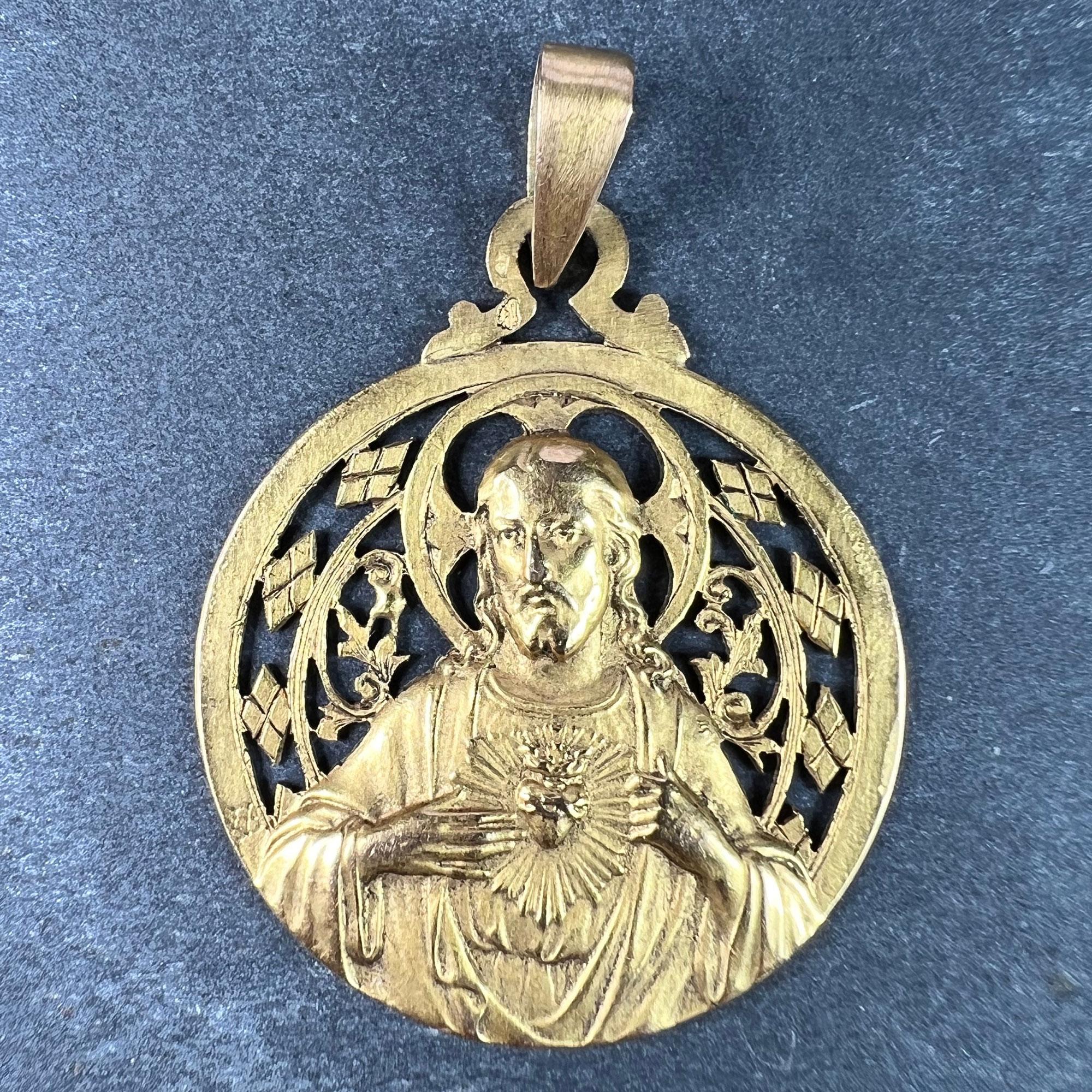 A French 18 karat (18K) yellow gold charm pendant designed as a round medal with a relief of Jesus Christ with the Sacred Heart with a pierced surround of diamonds and plant motifs surrounding His halo. Signed A Lavrillier for Andre Lavrillier