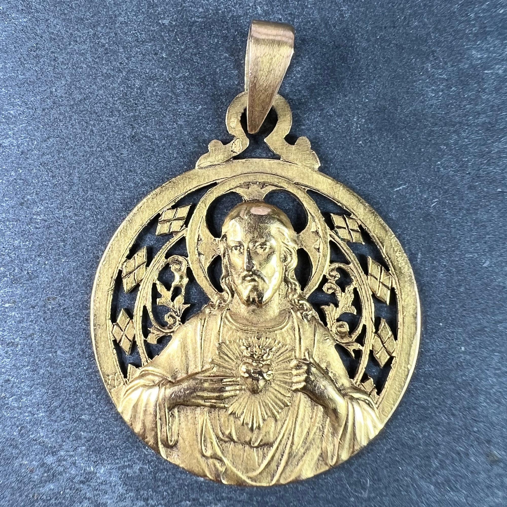 Pendentif à breloques en or jaune 18 carats (18K) conçu comme une médaille ronde avec un relief de Jésus-Christ au Sacré-Cœur avec un entourage ajouré de diamants et de motifs végétaux entourant son auréole. Signé A Lavrillier pour Andre Lavrillier