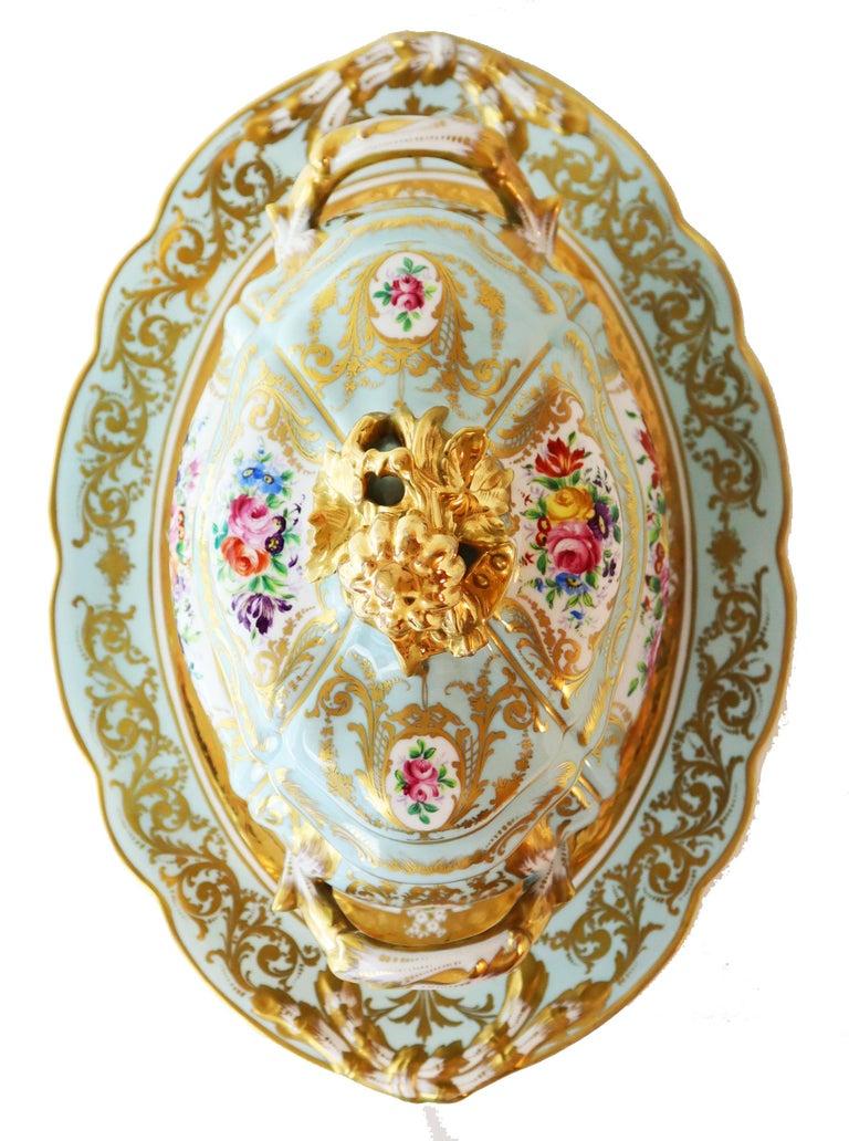 Diese französische paketvergoldete Porzellansoupière mit Deckel und Tablett aus der Mitte des 20. Jahrhunderts hat eine ovale Form und ist im Stil des Rokoko gehalten. Es handelt sich um ein Stück im Sèvres-Stil mit einem ovalen Bombenkorpus, in