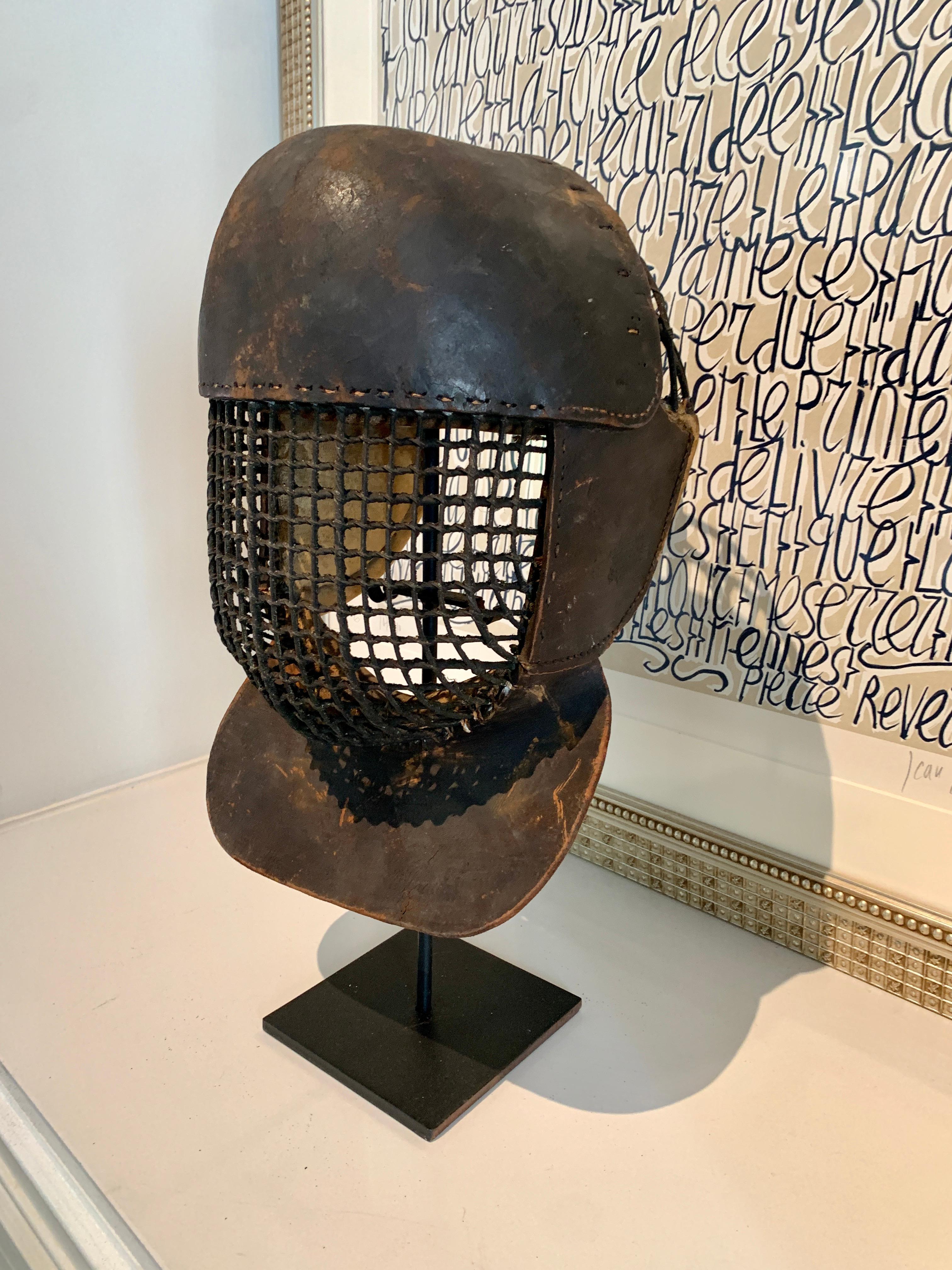 A heavily Patinated 19th century leather Fencing mask. An extraordinary piece, with beautifully hand stitched leather, metal front grill and Padded fabric lined head piece - an original ribbon hangs from the reverse. Highly decorative and a