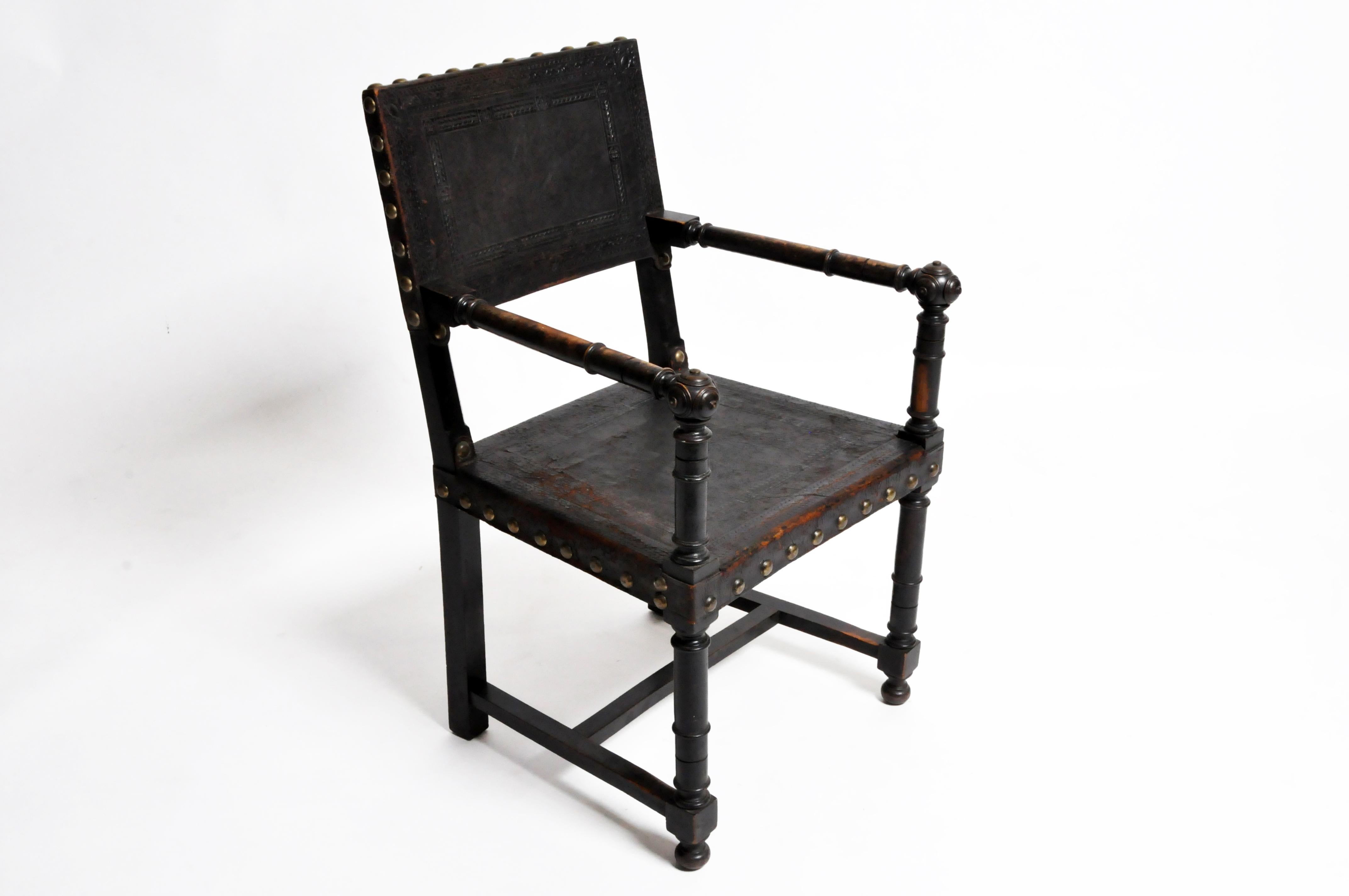 This armchair is from France and is made from black leather and wood, circa 1900. The chair features a beautifully aged patina and is made in a Gothic Revival style.