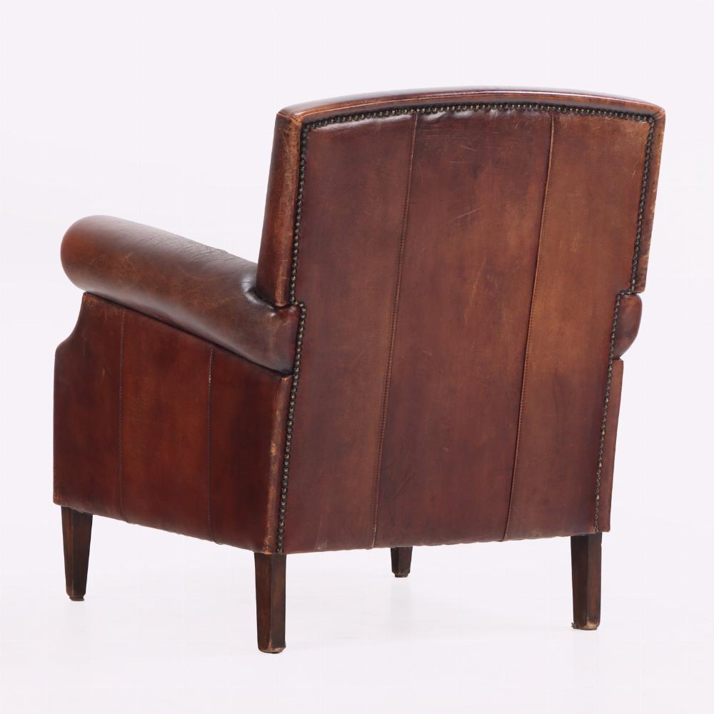 This warmly colored, well-maintained leather armchair has a lovely patina and is beautifully finished with decorative nails. It will enhance your office, game room or view of the fireplace in your living room.