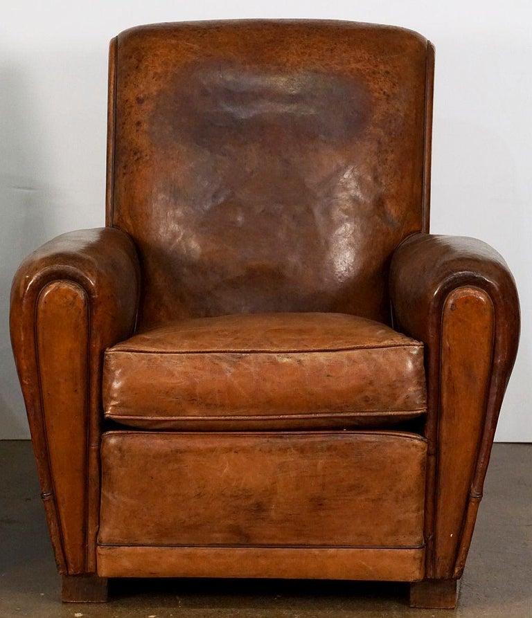 Un beau fauteuil club ou de salon en cuir français de l'époque Art Déco - avec un dossier et une assise confortables avec un coussin amovible, des accoudoirs élégants en cuir d'origine, une garniture de clous en laiton à l'arrière, et reposant sur