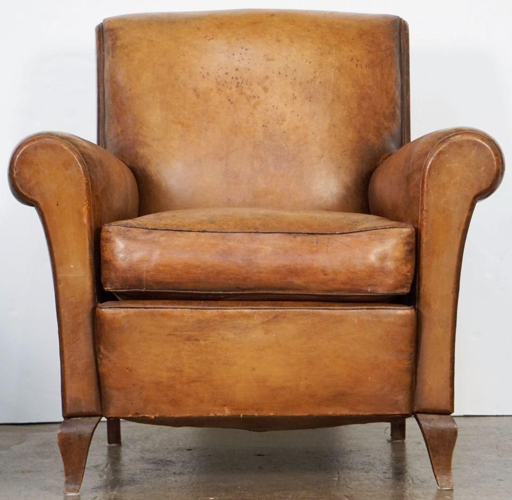 A handsome vintage French leather upholstered club or lounge chair from the Art Deco era - featuring a comfortable shaped back and seat with removable cushion, with stylish arms and original leather, brass nail-head trim to back, and resting on