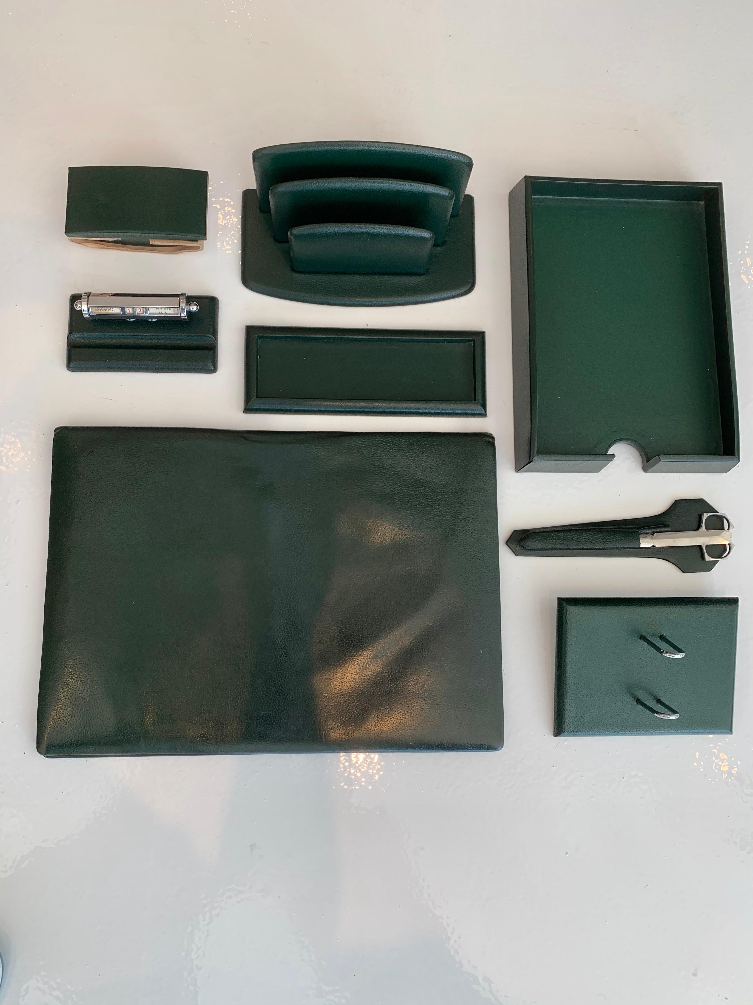 Fantastic 8 piece French leather desk set by Le Tanneur. All pieces wrapped in dark green leather. Desk set includes : desk pad, paper holder, pen holder, ink blotter, mail holder, adjustable calendar, chrome scissors and letter opener and a