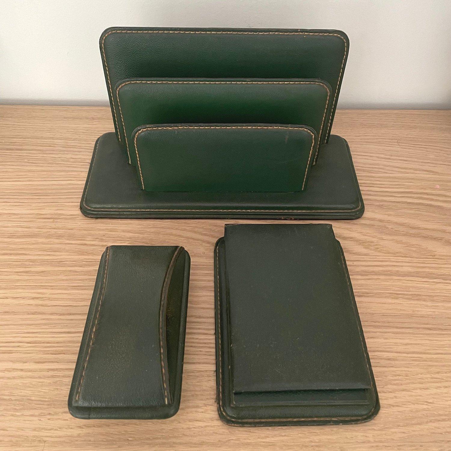 French leather desk set in the style of Jacques Adnet.
Forest green leather with contrast stitching.
Patina from age and use.
Natural color variations within the distressed leather.
Perfectly worn in.
Rich with character and charm.

Three